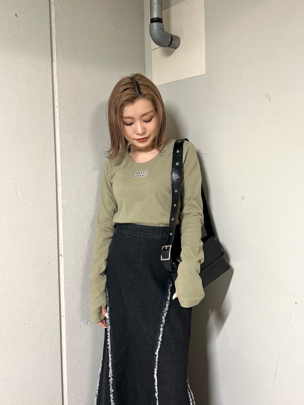 グリーン系のTシャツ/カットソー、ブラック系のデニムスカート、ブラック系のブーツを着用したレディースの冬コーディネートの4枚目の写真