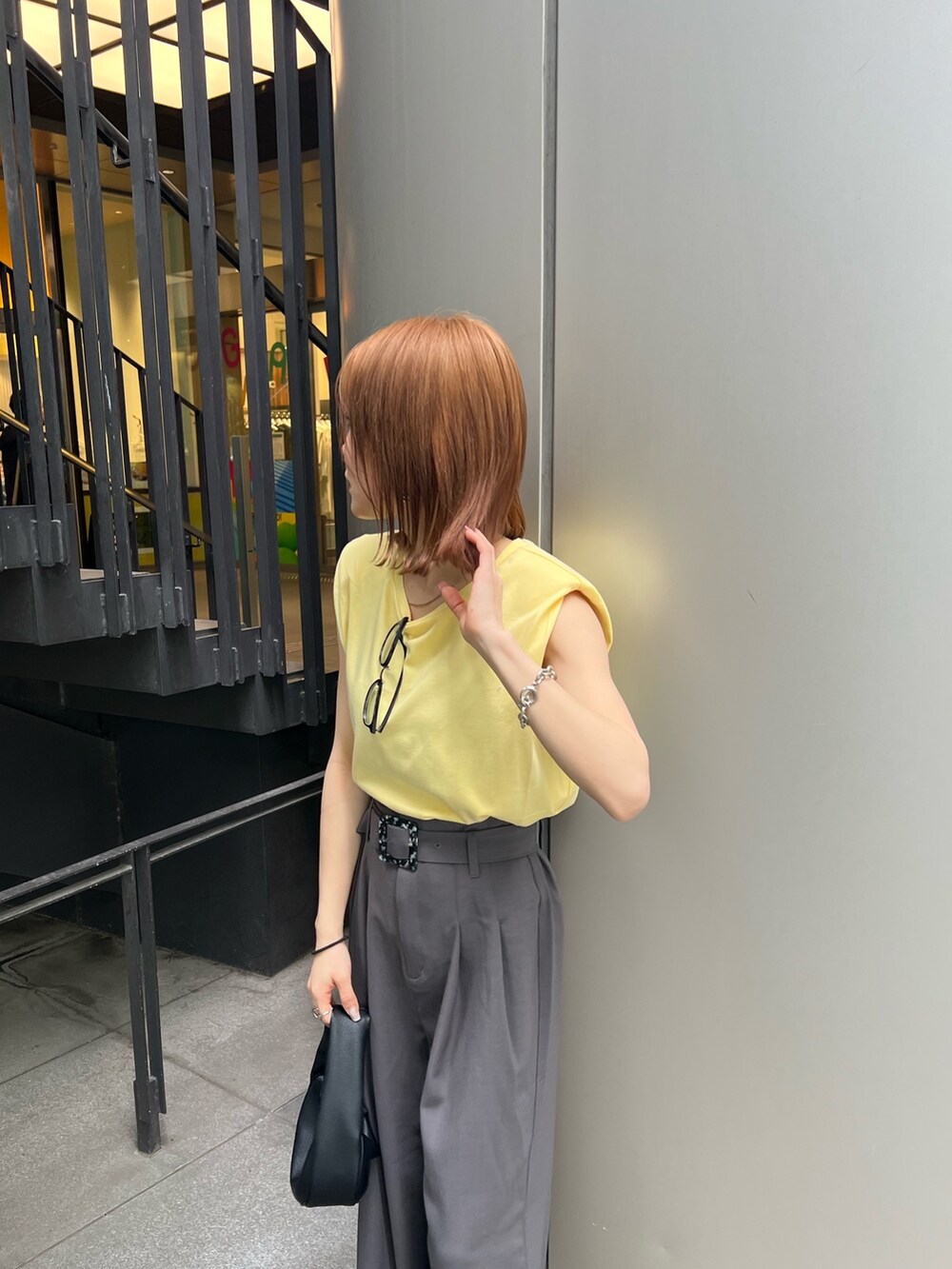 ブラック系のサンダル、グレー系のスラックス、イエロー系のTシャツ/カットソーを着用したレディースの春コーディネートの7枚目の写真