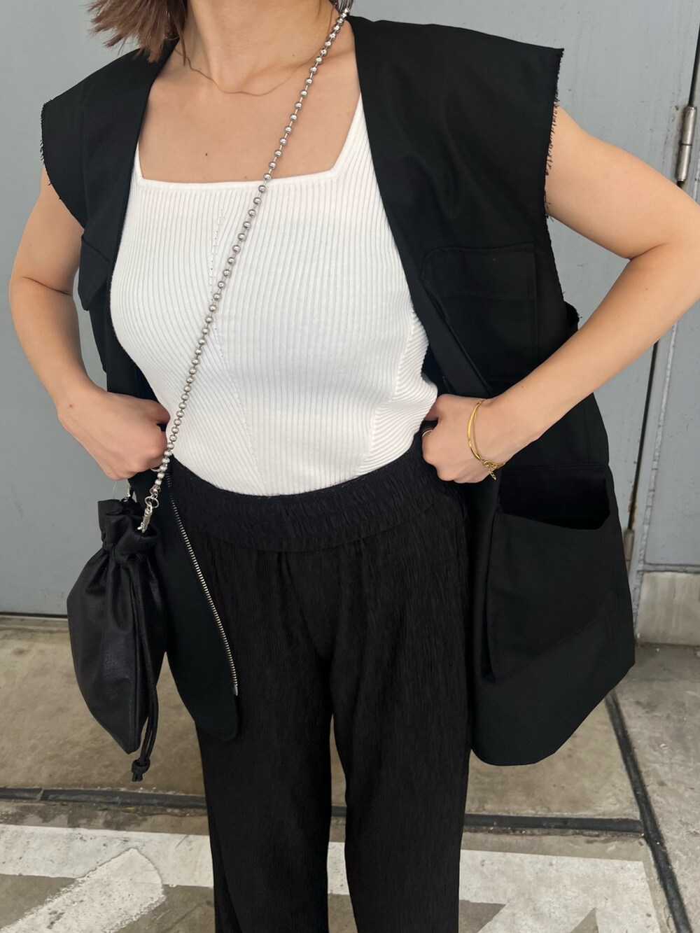 ブラック系のベスト、ホワイト系のニット/セーター、ブルー系のキャップを着用したレディースの夏コーディネートの7枚目の写真