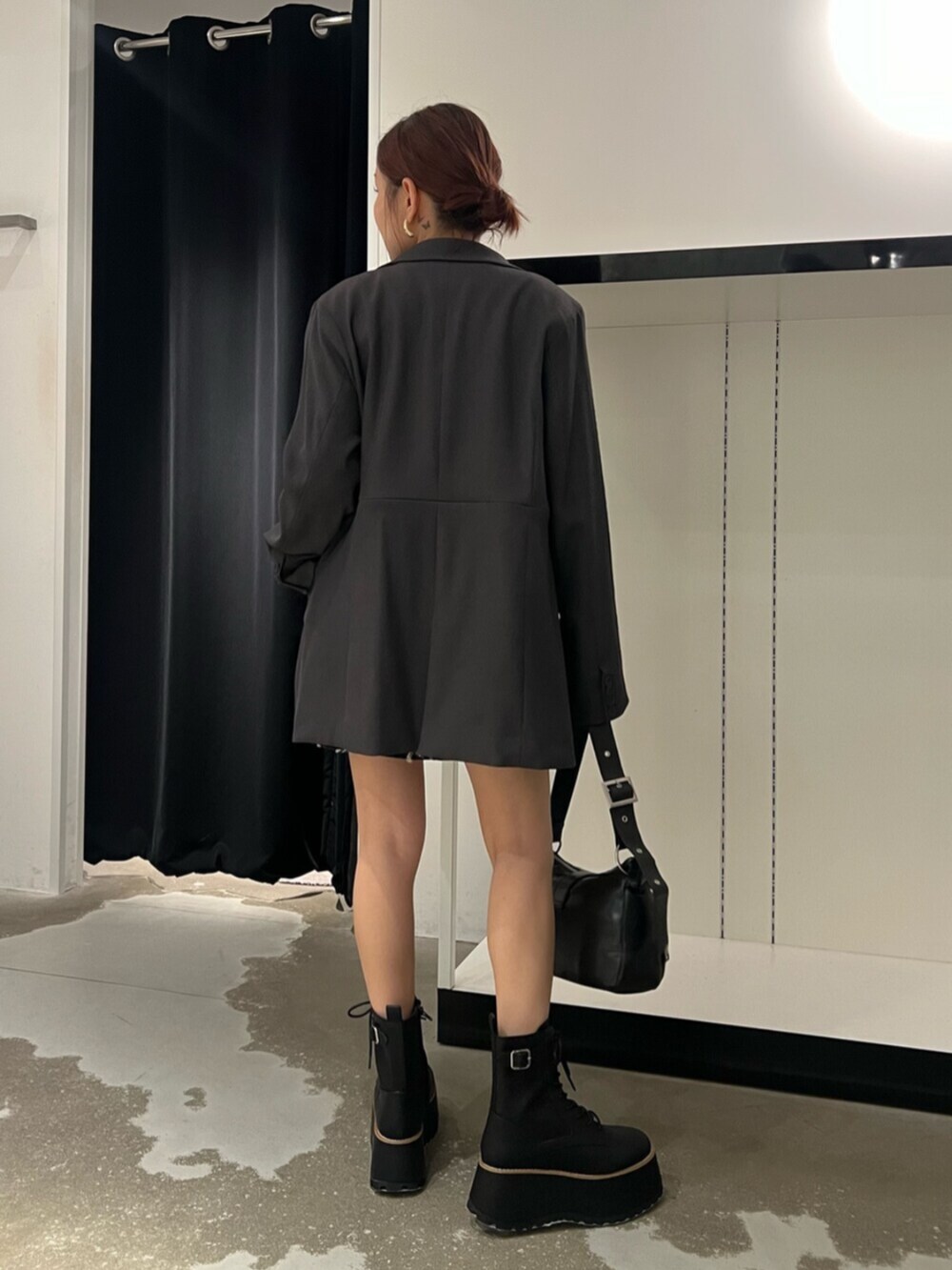 ブラック系のハンドバッグ、ブラウン系のブーツ、ブラック系のニット/セーターを着用したレディースの秋コーディネートの3枚目の写真