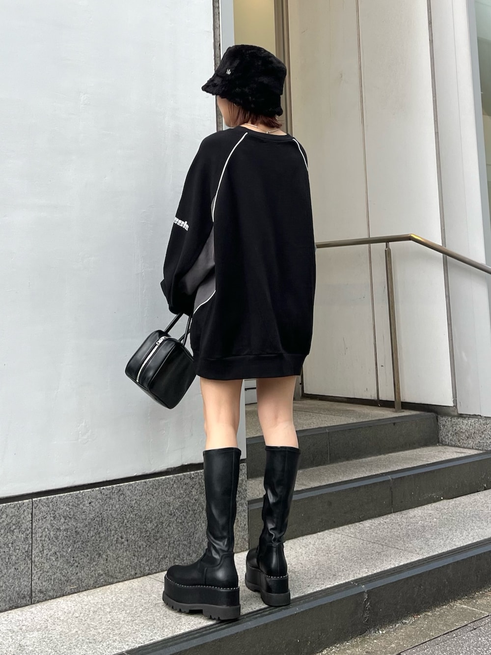 ブラック系のスウェット、ブラック系のブーツ、ブラック系のハットを着用したレディースの秋コーディネートの3枚目の写真