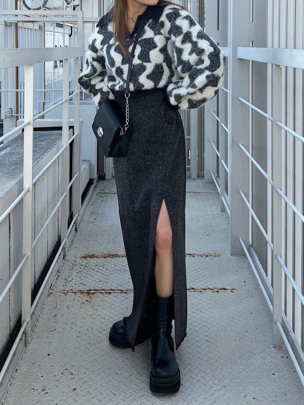 ブラック系のニット/セーター、ブラック系のスカート、ブラック系のショルダーバッグを着用したレディースの秋コーディネートの2枚目の写真