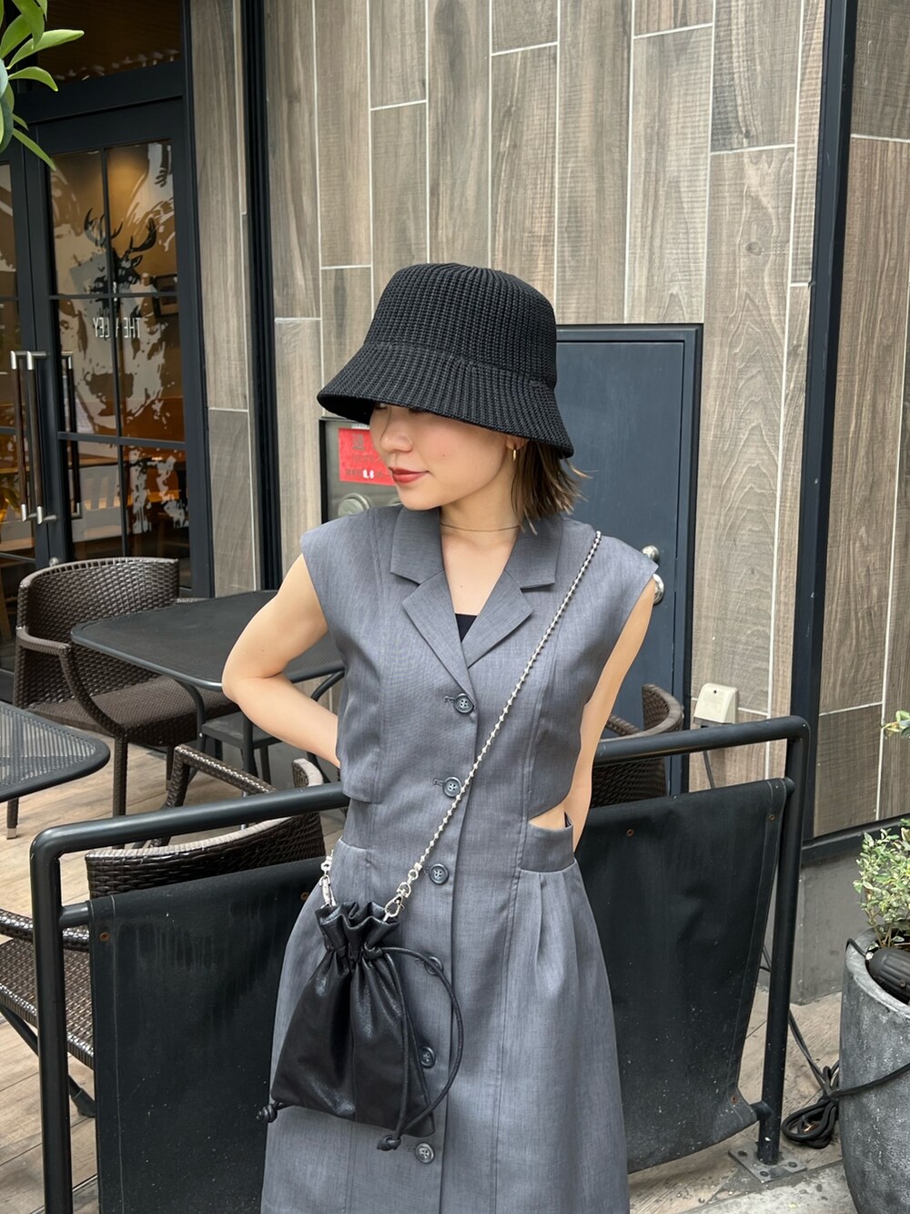 グレー系のワンピース、ブラック系のショルダーバッグ、ブラック系のブーツを着用したレディースの春コーディネートの4枚目の写真