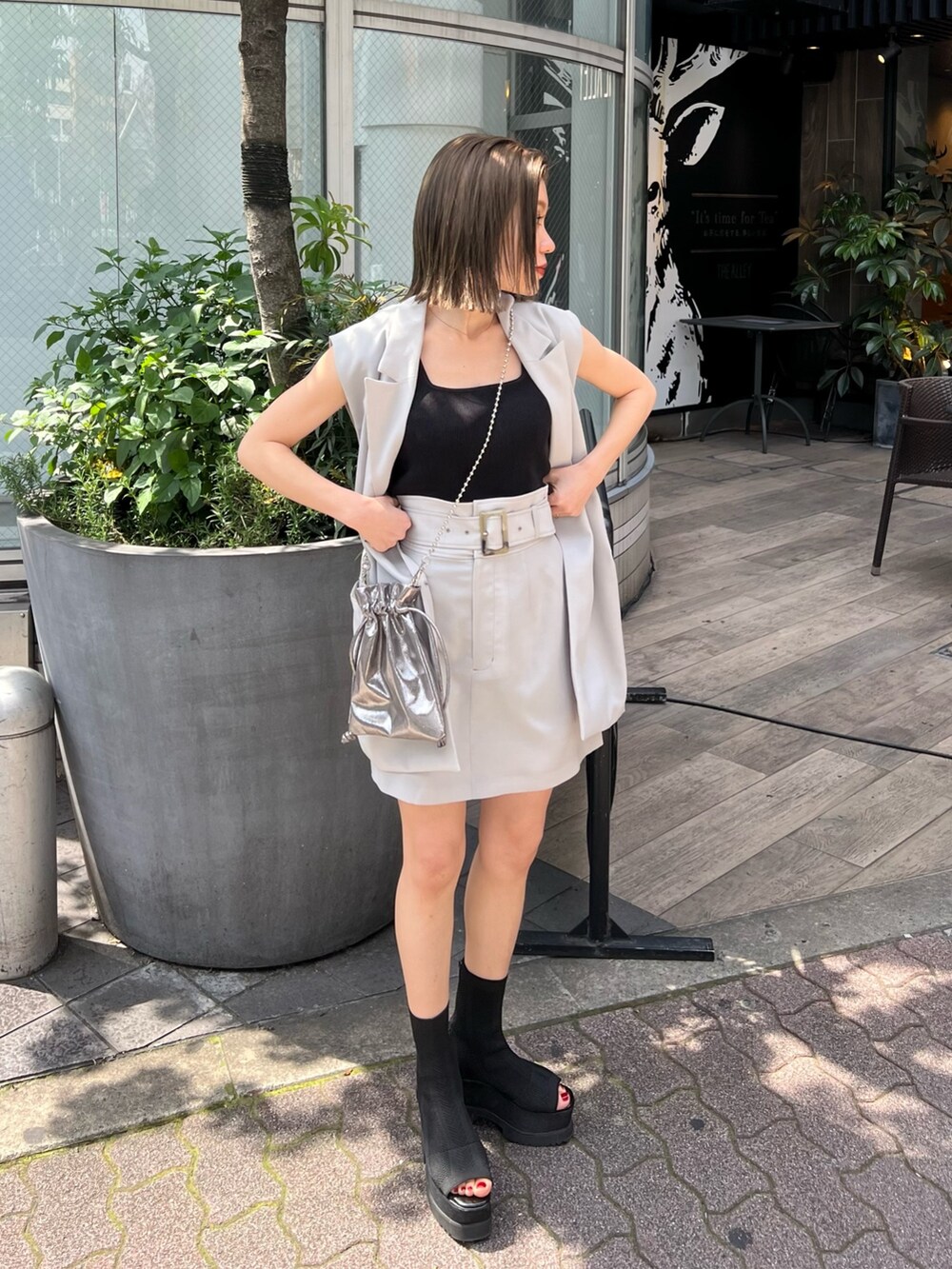 グレー系のベスト、ブラック系のブーツ、グレー系のスカートを着用したレディースの春コーディネートの2枚目の写真