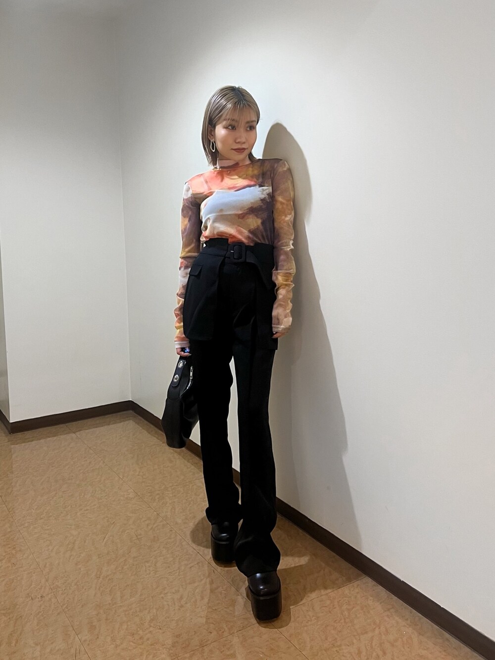 オレンジ系のTシャツ/カットソー、ブラック系のブーツ、ブラック系のスラックスを着用したレディースの夏コーディネートの3枚目の写真