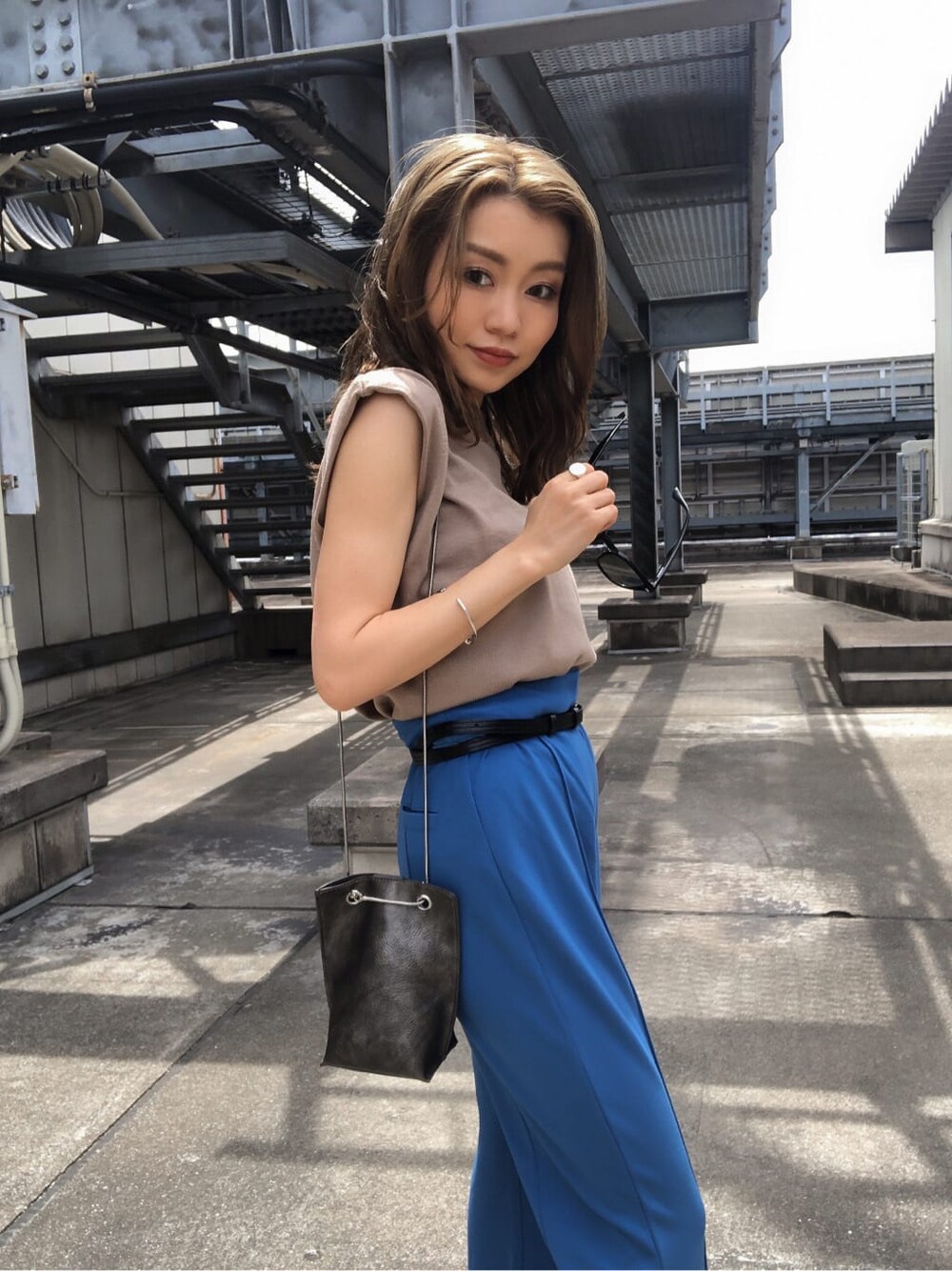 ブルー系のスラックス、ブラック系のサンダル、ベージュ系のタンクトップを着用したレディースの夏コーディネートの2枚目の写真