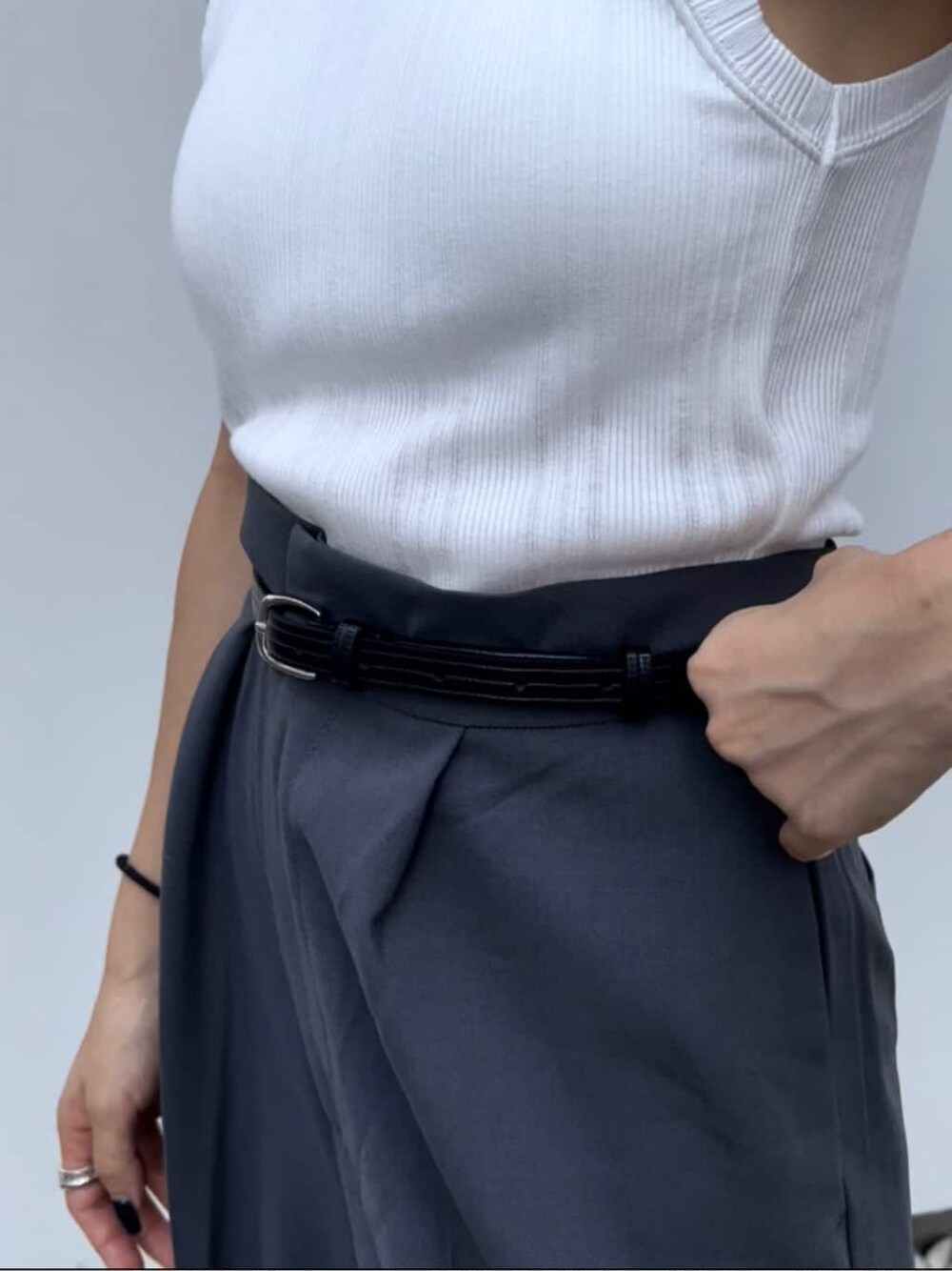 ホワイト系のタンクトップ、グレー系のスラックス、ブラック系のベルトを着用したレディースの夏コーディネートの6枚目の写真