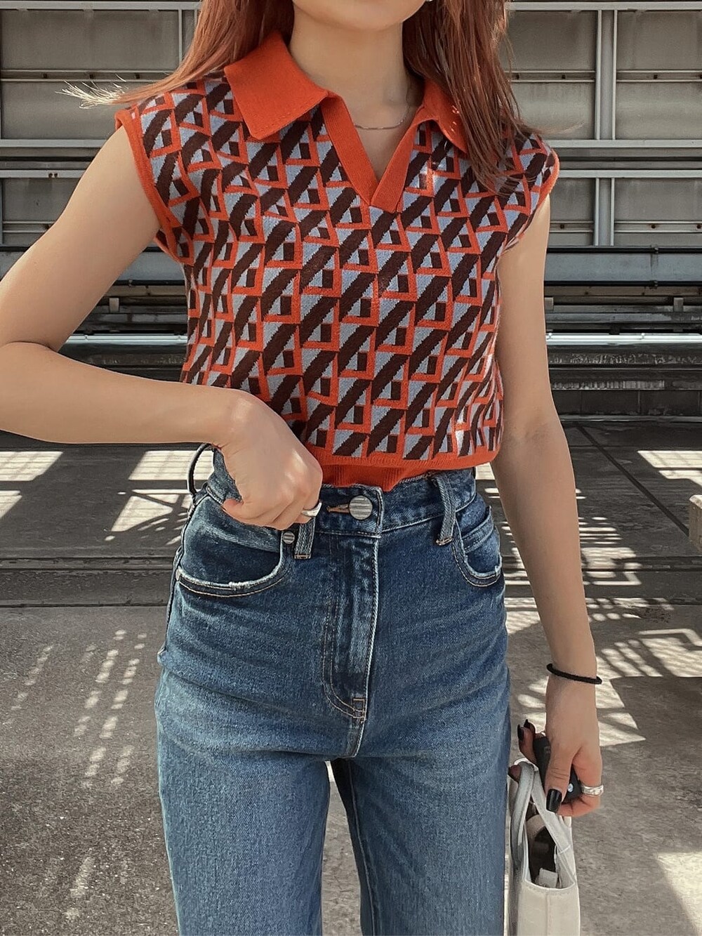 ブルー系のデニムパンツ、オレンジ系のニット/セーター、ホワイト系のブーツを着用したレディースの夏コーディネートの6枚目の写真