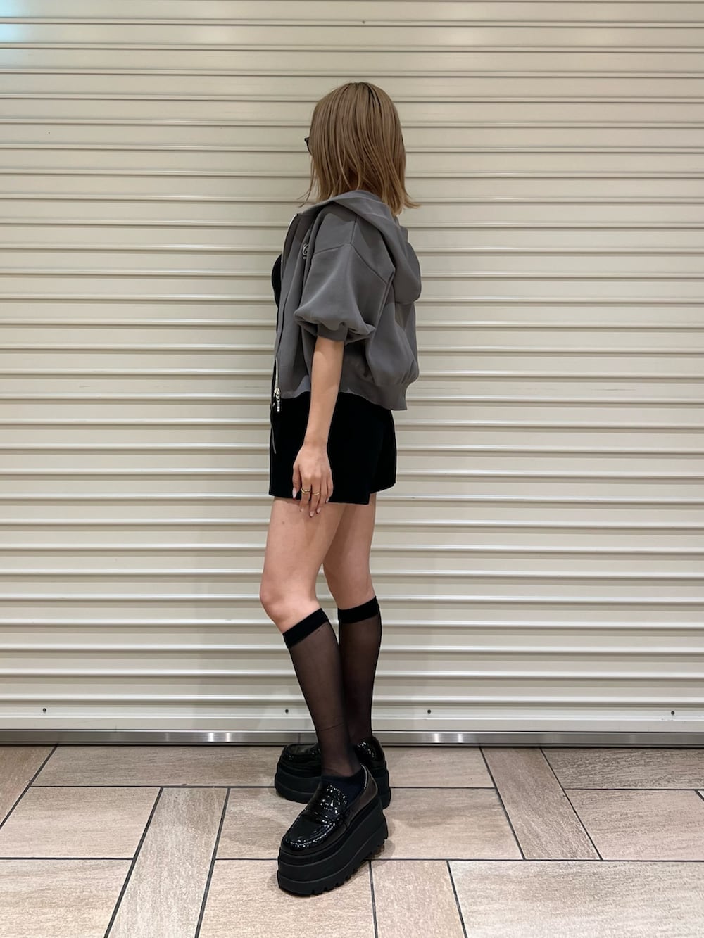 グレー系のパーカー、ブラック系のスカートを着用したレディースの夏コーディネートの2枚目の写真