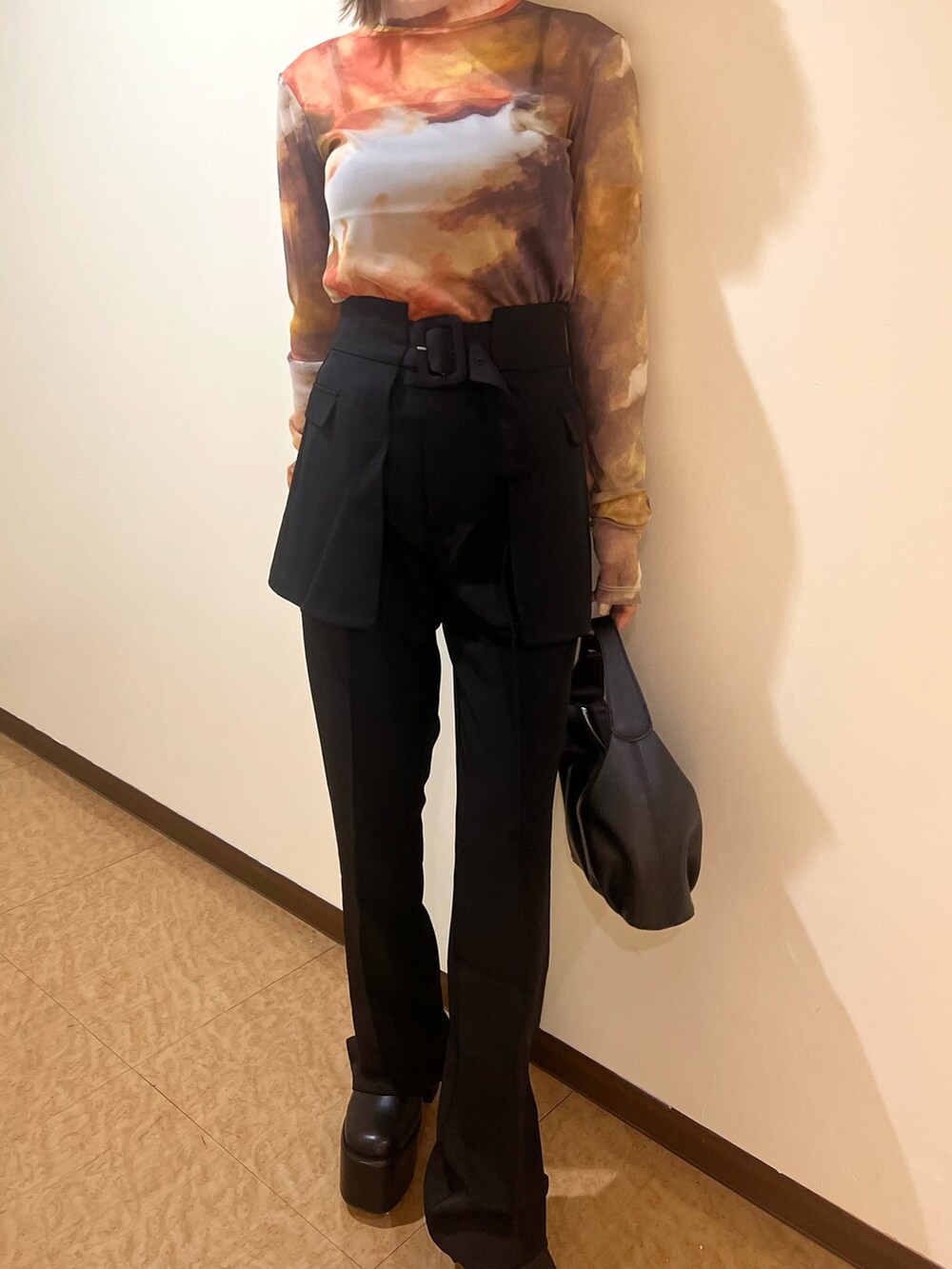 オレンジ系のTシャツ/カットソー、ブラック系のブーツ、ブラック系のスラックスを着用したレディースの夏コーディネートの6枚目の写真