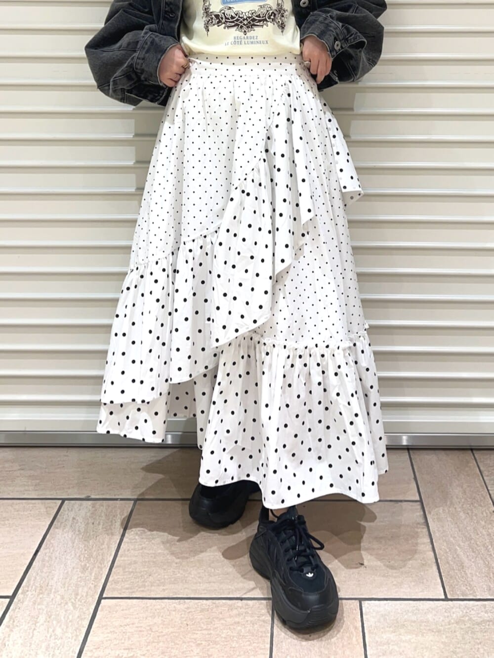 イエロー系のTシャツ/カットソー、ブラック系のデニムジャケット、ホワイト系のスカートを着用したレディースの春コーディネートの6枚目の写真