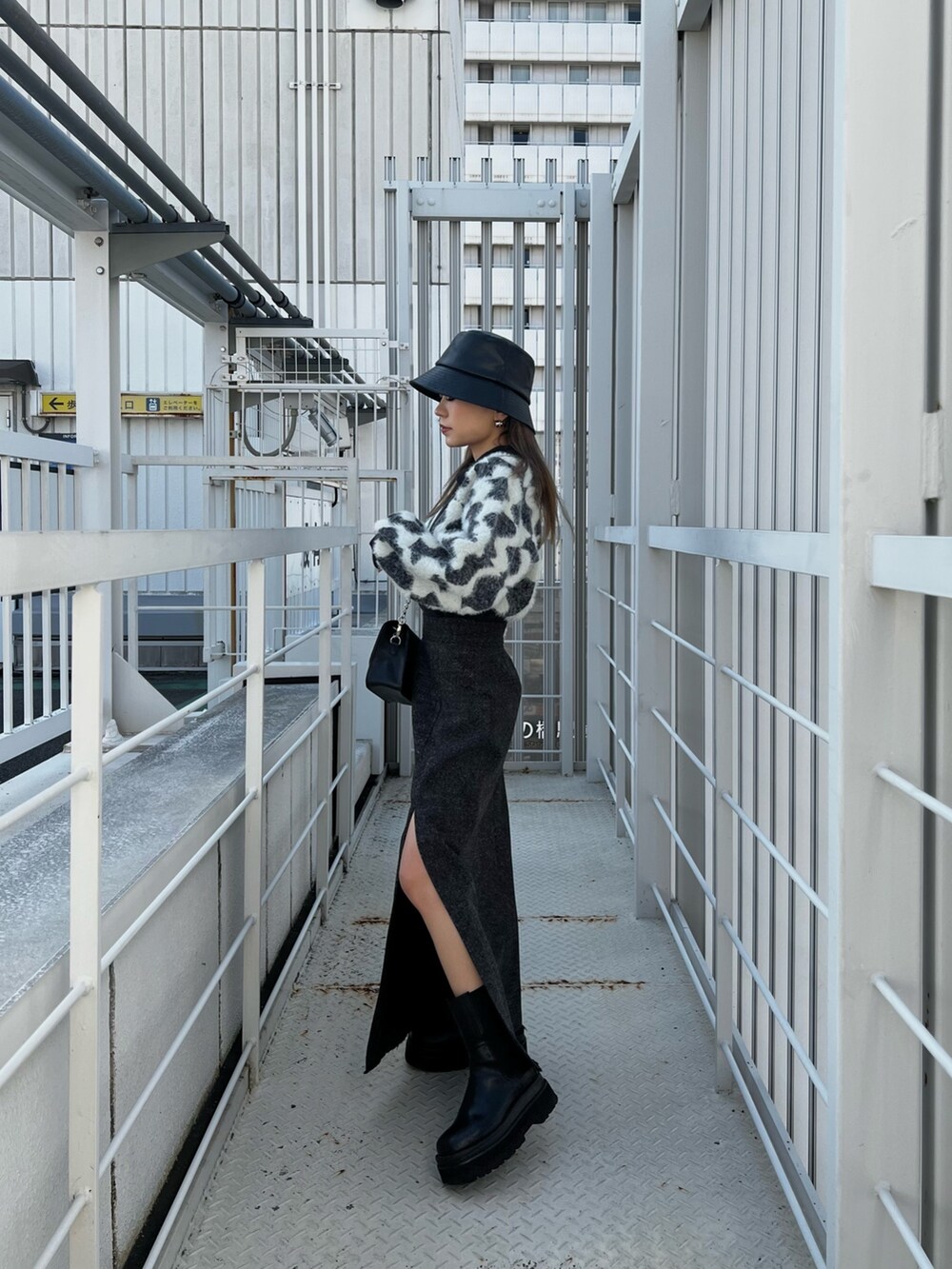 ブラック系のニット/セーター、ブラック系のスカート、ブラック系のショルダーバッグを着用したレディースの秋コーディネートの3枚目の写真