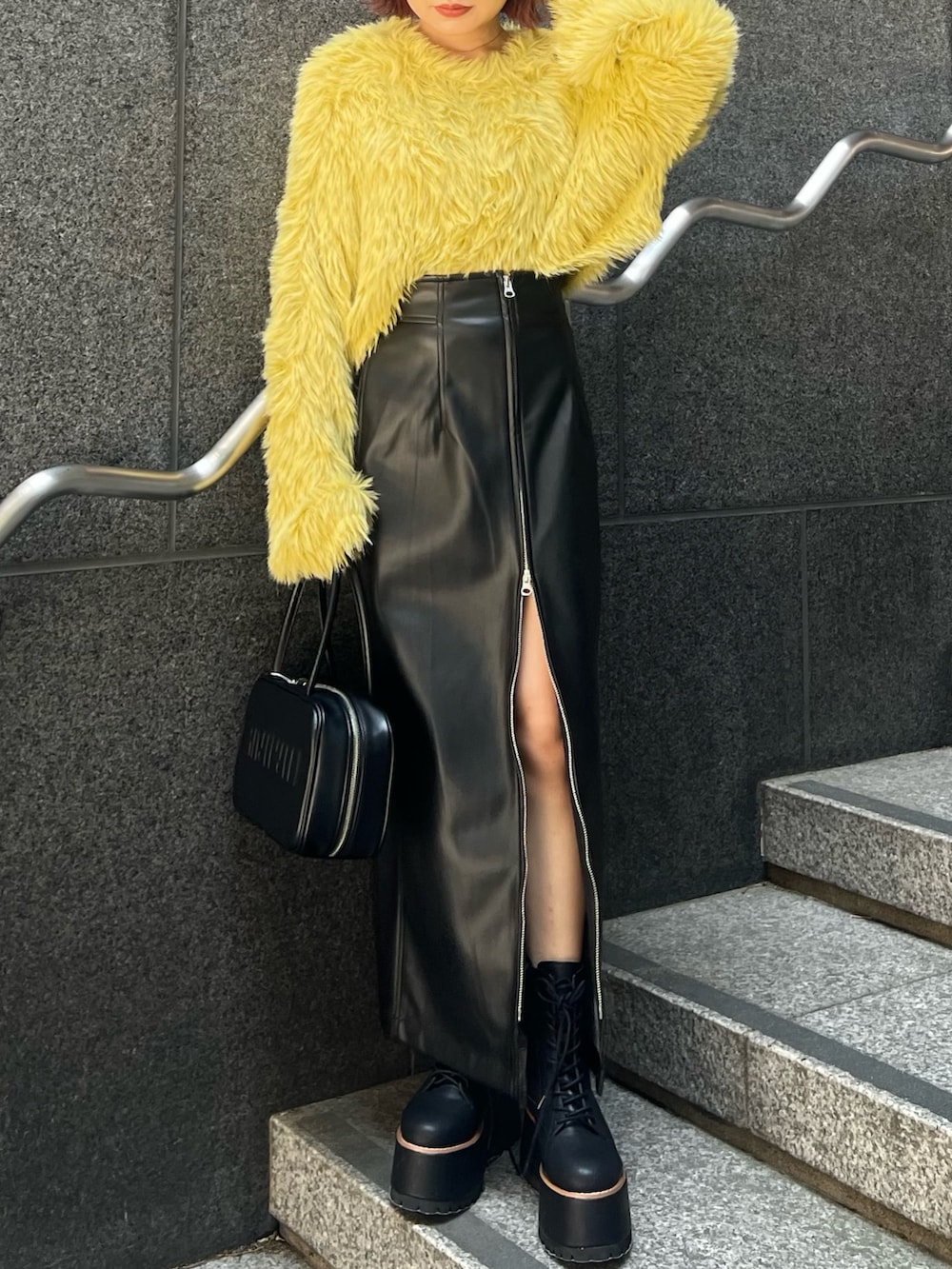 イエロー系のニット/セーター、ブラック系のスカート、ブラック系のブーツを着用したレディースの秋コーディネートの7枚目の写真