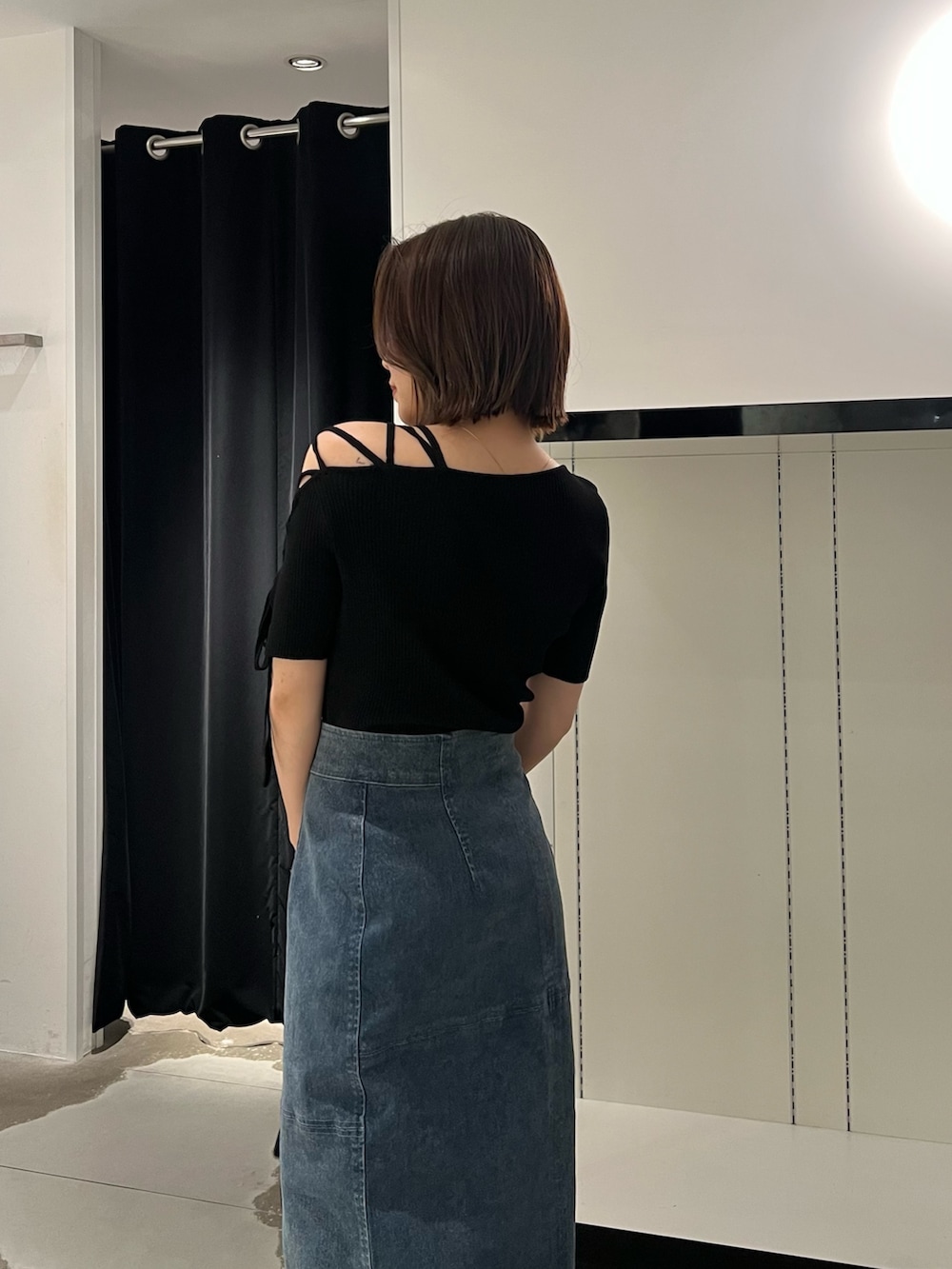 ブルー系のデニムスカート、ブラック系のニット/セーター、ブラック系のサンダルを着用したレディースの夏コーディネートの6枚目の写真