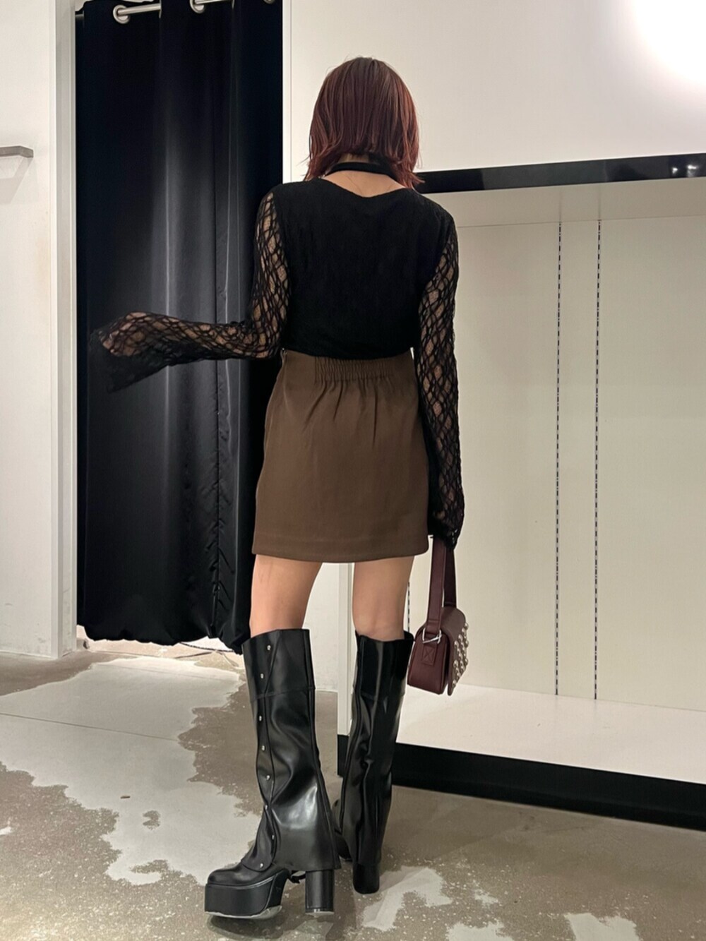 ブラック系のTシャツ/カットソー、ブラウン系のスカート、ブラック系のブーツを着用したレディースの秋コーディネートの2枚目の写真