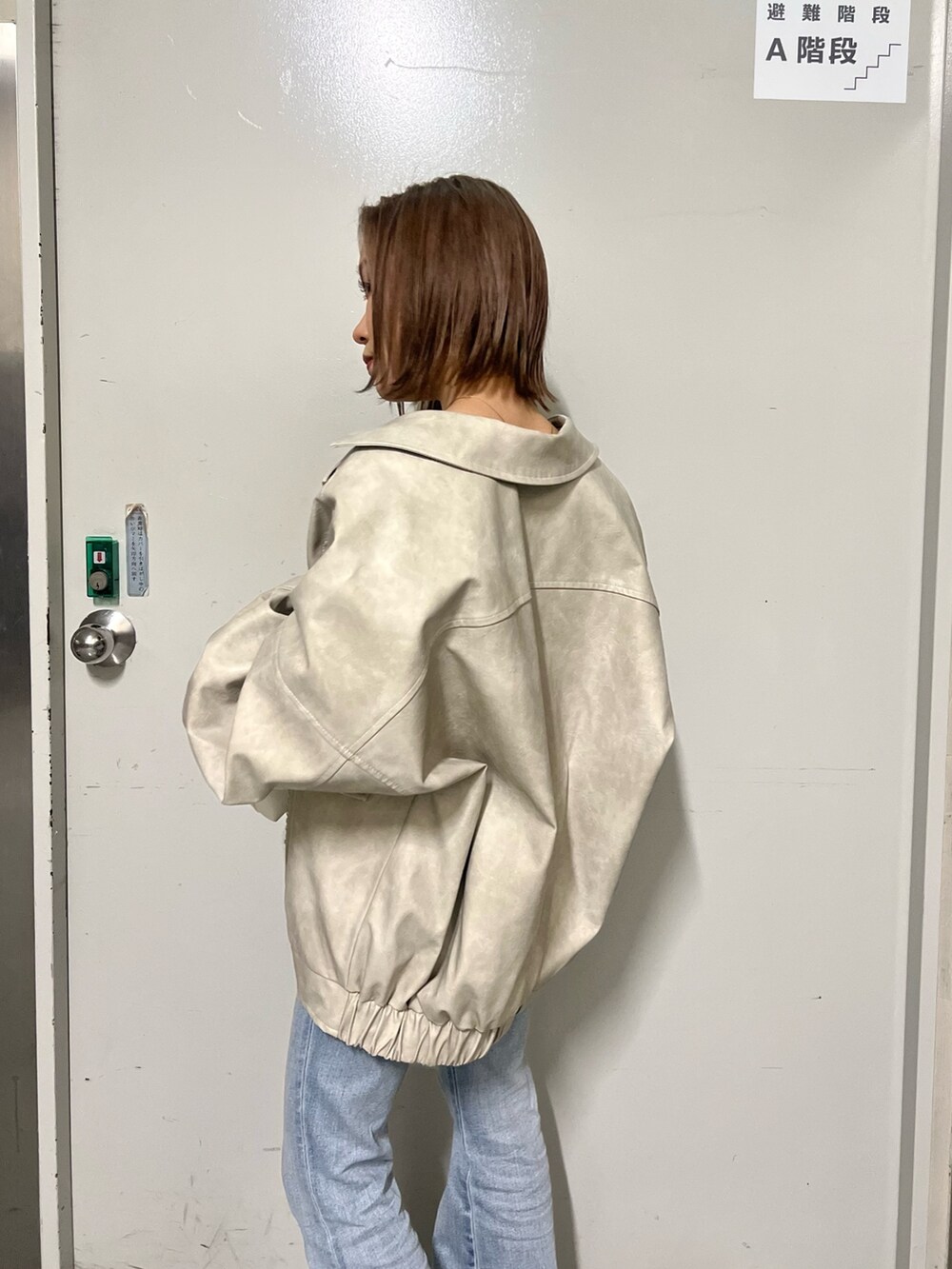 ホワイト系のブルゾン、ホワイト系のニット/セーター、ホワイト系のハンドバッグを着用したレディースの冬コーディネートの6枚目の写真