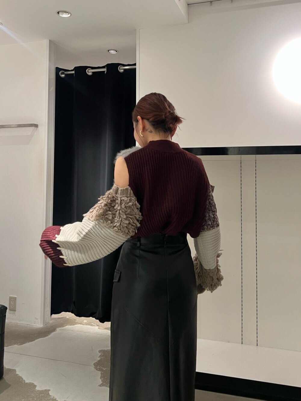 ブラック系のブーツ、レッド系のニット/セーター、ブラック系のスカートを着用したレディースの秋コーディネートの6枚目の写真