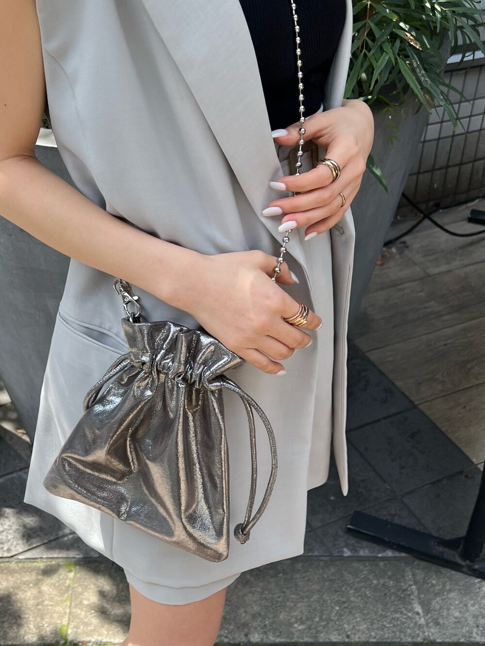 グレー系のベスト、ブラック系のブーツ、グレー系のスカートを着用したレディースの春コーディネートの8枚目の写真