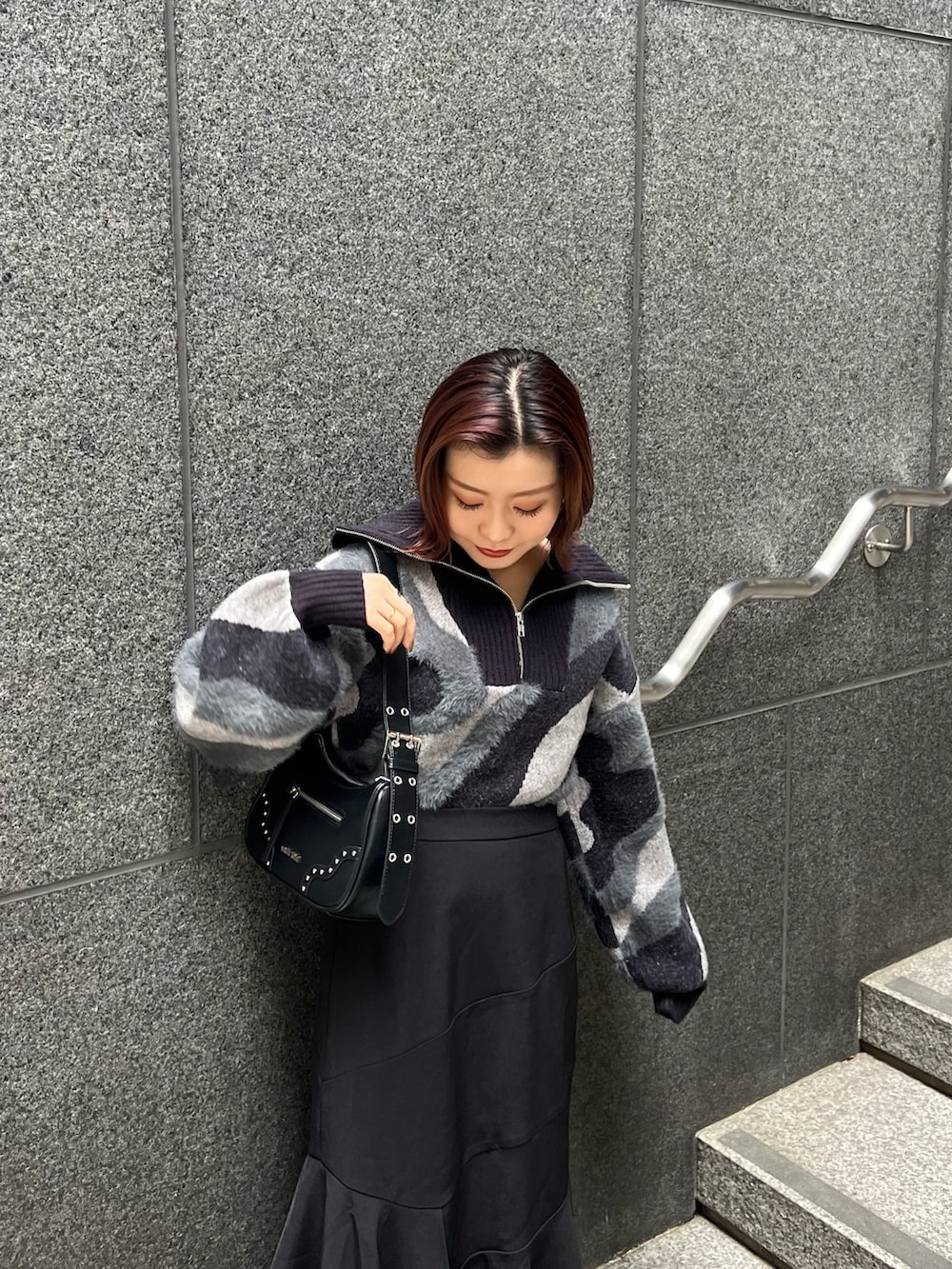 ブラック系のニット/セーター、ブラウン系のブーツ、ブラック系のスカートを着用したレディースの秋コーディネートの6枚目の写真