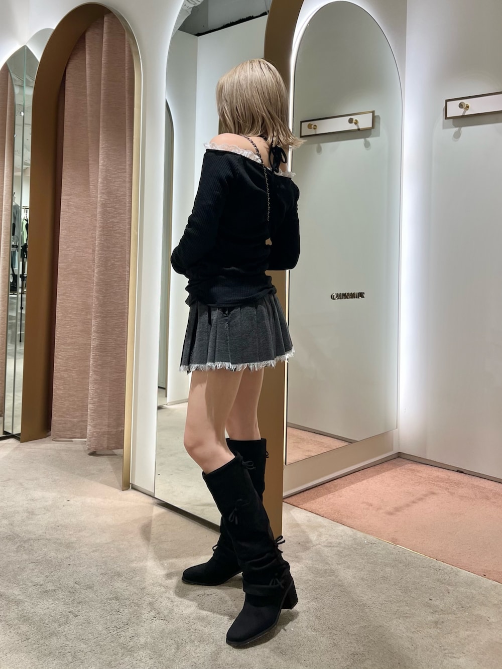 ブラック系のブーツ、ブラック系のスカートを着用したレディースの秋コーディネートの2枚目の写真