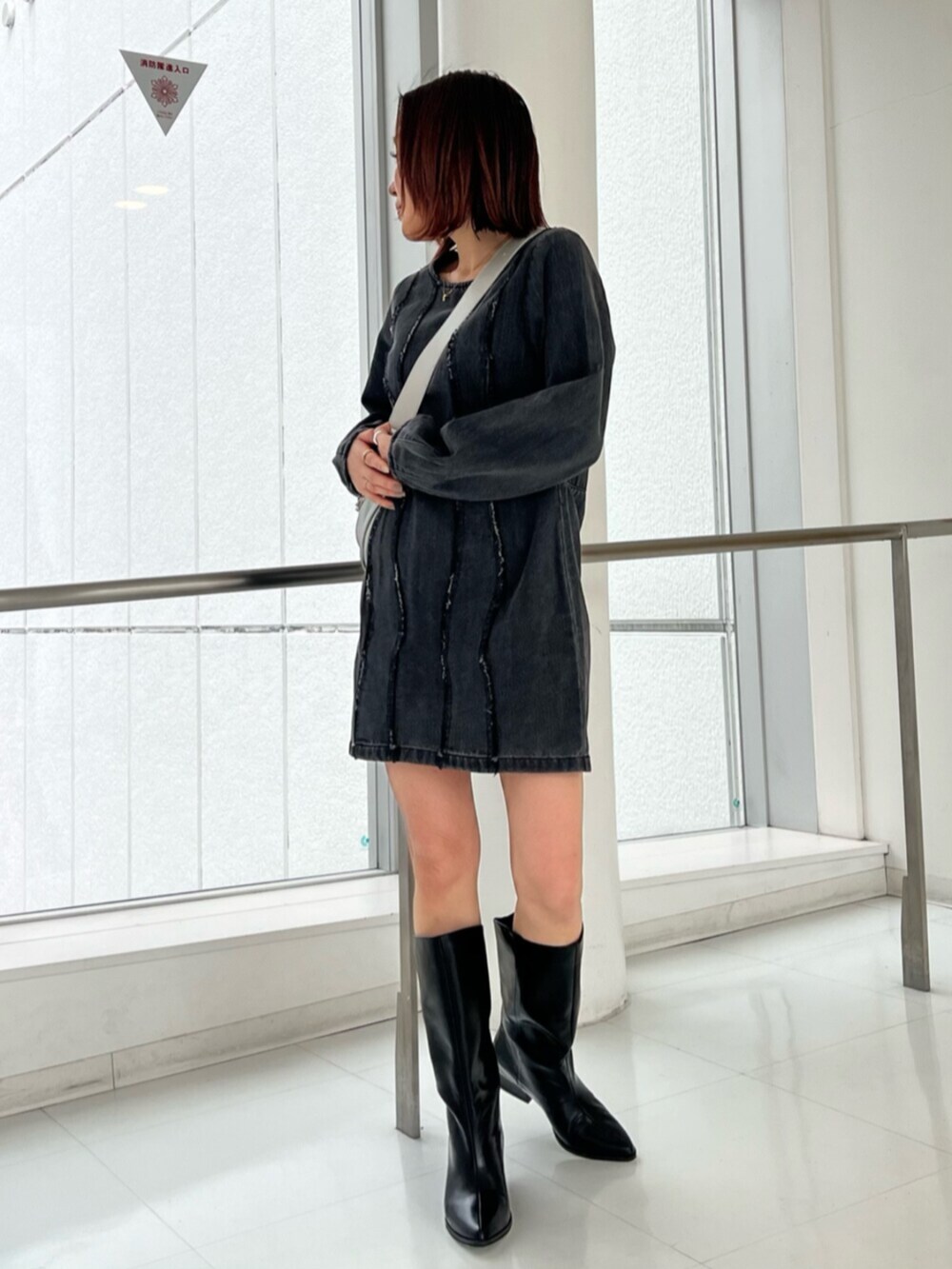 シルバー系のショルダーバッグ、ブラック系のワンピース、ブラック系のブーツを着用したレディースの冬コーディネートの2枚目の写真