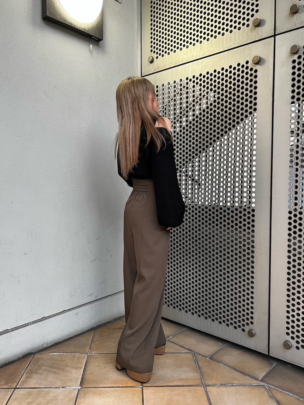 ブラック系のニット/セーター、ブラウン系のスラックス、ブラック系のローファーを着用したレディースの冬コーディネートの3枚目の写真