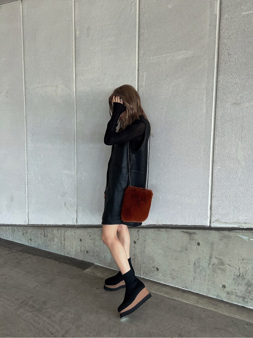 ブラック系のニット/セーター、ブラウン系のショルダーバッグ、ブラック系のワンピースを着用したレディースの秋コーディネートの4枚目の写真