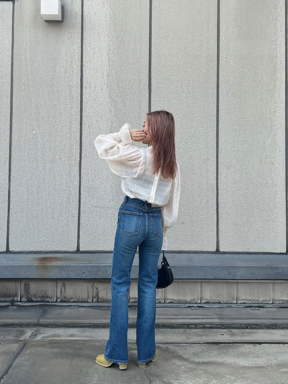 ブルー系のデニムパンツ、ホワイト系のシャツ/ブラウス、ブラック系のハンドバッグを着用したレディースの夏コーディネートの2枚目の写真