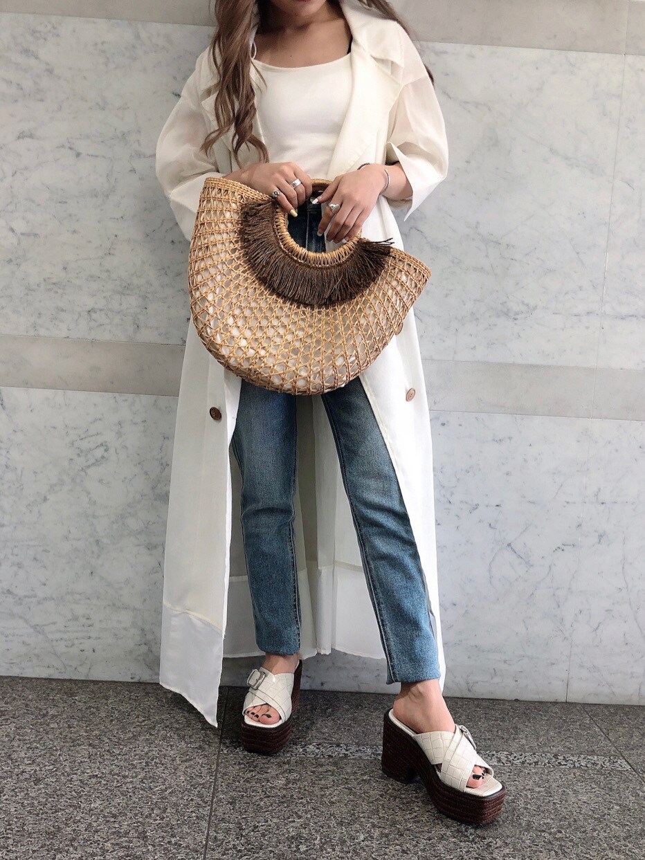 ホワイト系のキャミソール、ベージュ系のかごバッグ、ブルー系のデニムパンツを着用したレディースの春コーディネートの2枚目の写真