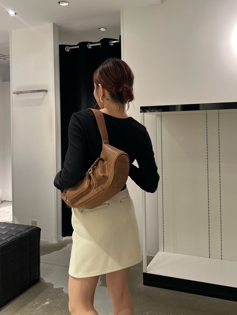 ホワイト系のスカート、ブラック系のTシャツ/カットソー、ブラック系のブーツを着用したレディースの秋コーディネートの6枚目の写真