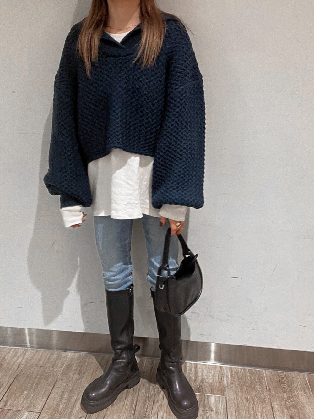 ブラック系のブーツ、ブルー系のニット/セーター、ブラック系のハンドバッグを着用したレディースの冬コーディネートの7枚目の写真