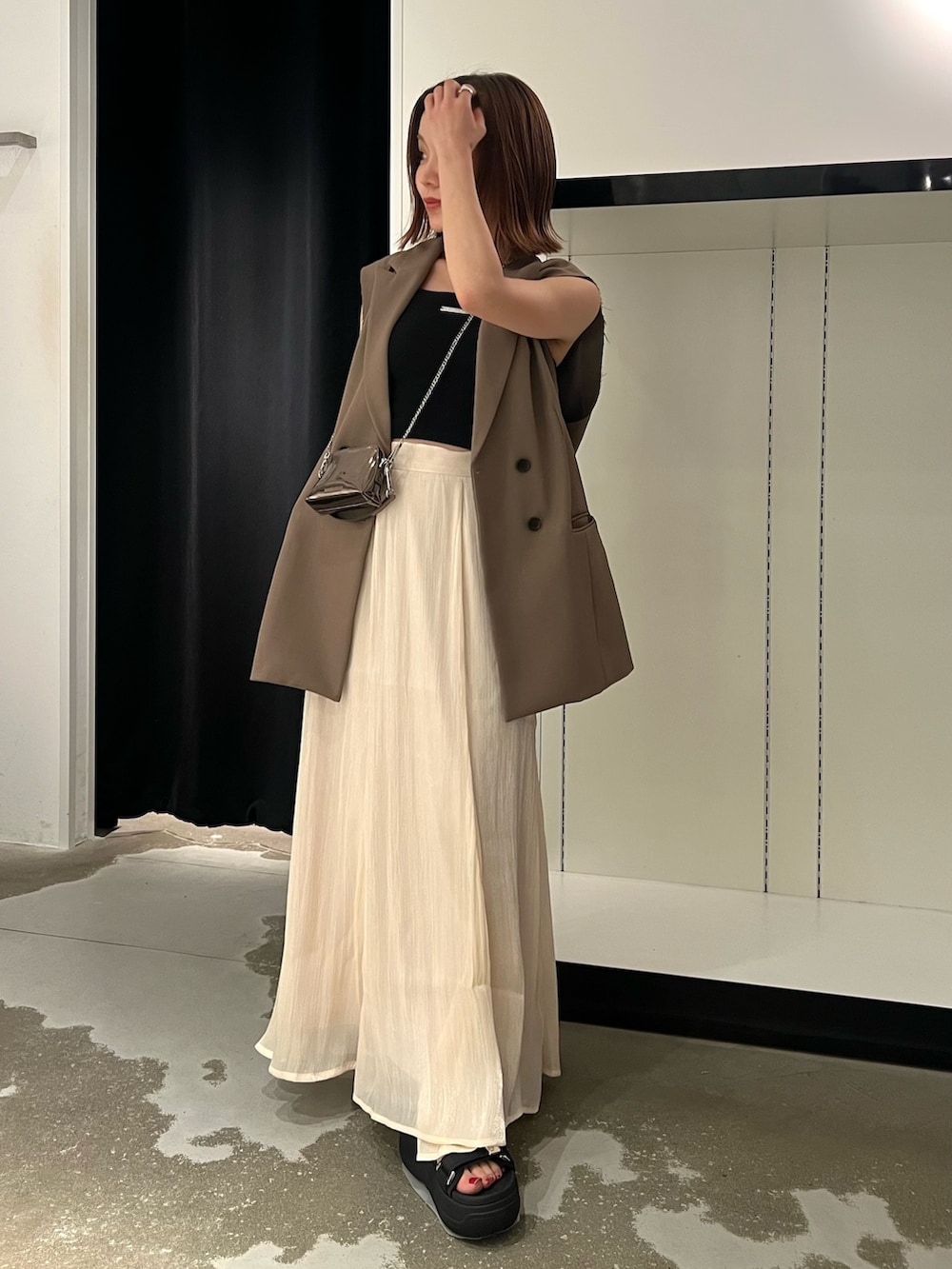 ブラック系のサンダル、ホワイト系のスカート、ゴールド系のショルダーバッグを着用したレディースの夏コーディネートの4枚目の写真