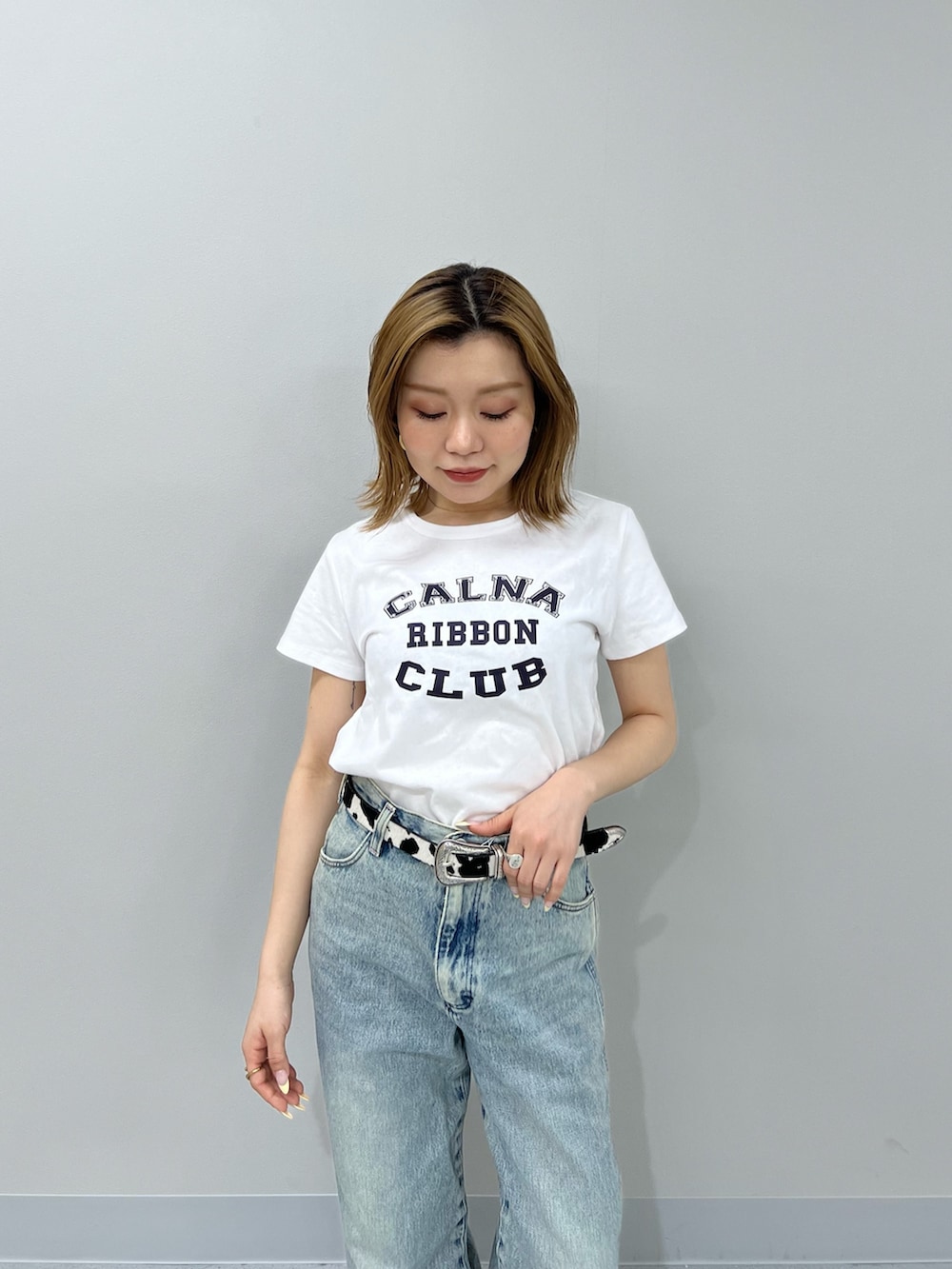 ブルー系のデニムパンツ、ホワイト系のTシャツ/カットソー、ブラウン系のブーツを着用したレディースの春コーディネートの4枚目の写真