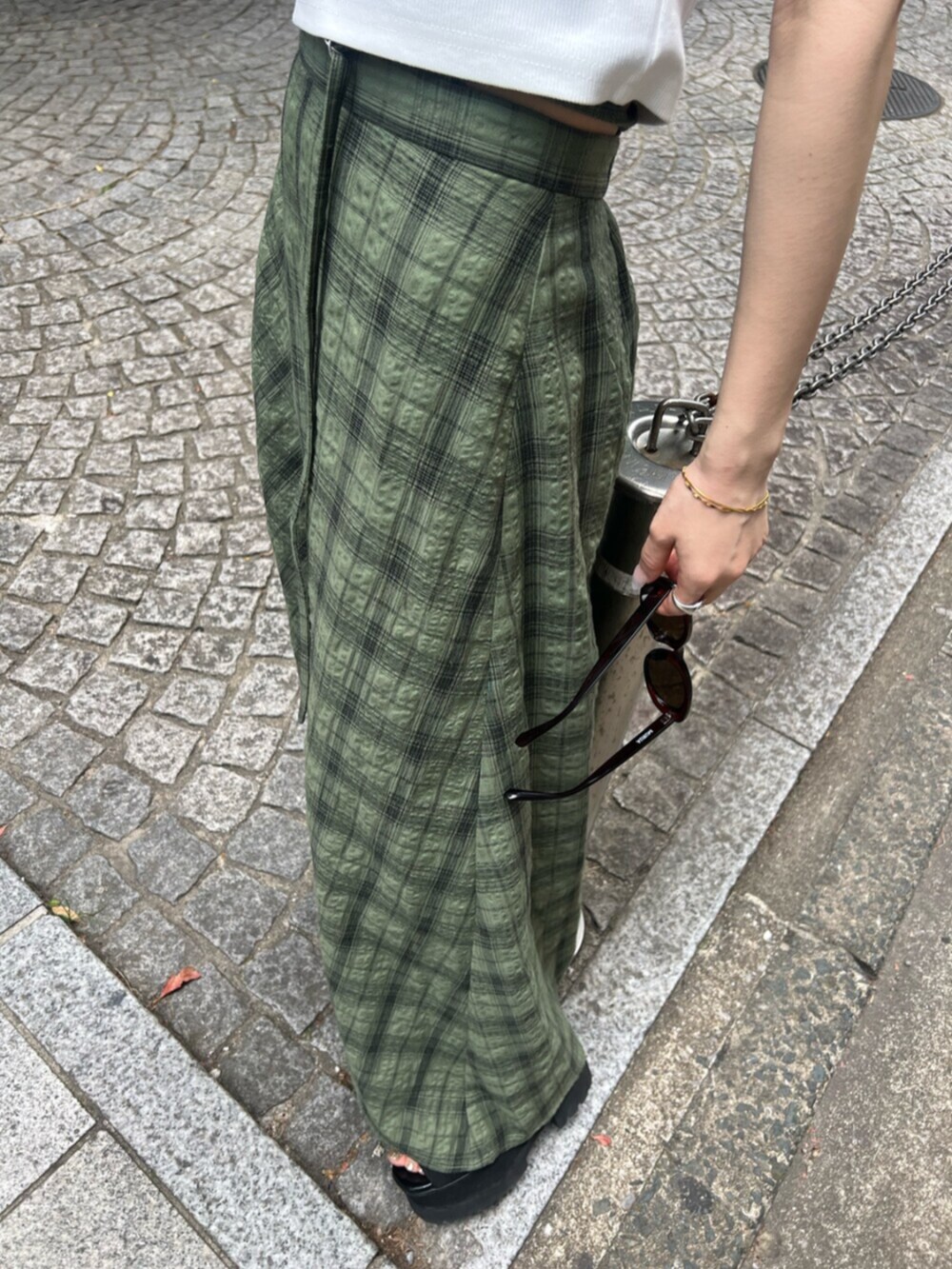 ブラック系のサンダル、ホワイト系のTシャツ/カットソー、グリーン系のスカートを着用したレディースの春コーディネートの7枚目の写真