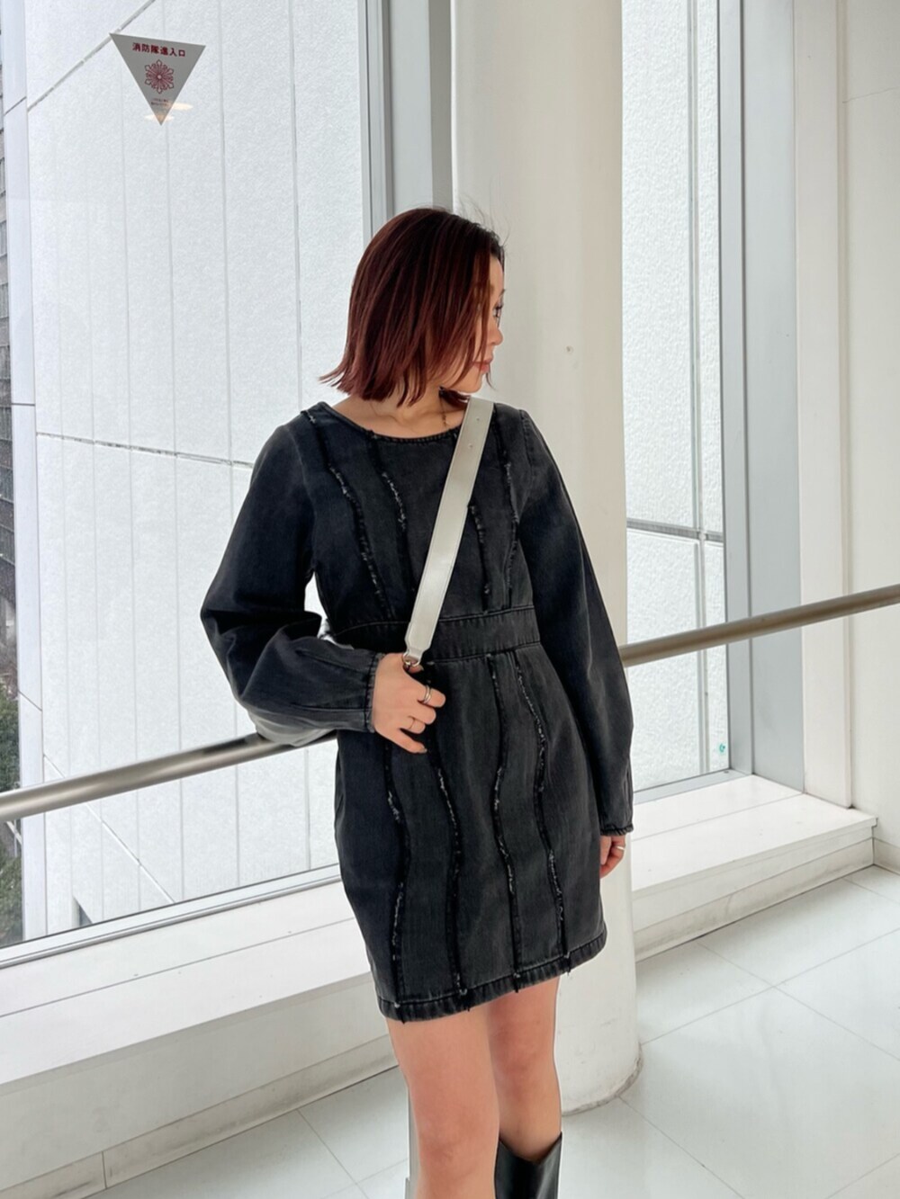 シルバー系のショルダーバッグ、ブラック系のワンピース、ブラック系のブーツを着用したレディースの冬コーディネートの5枚目の写真