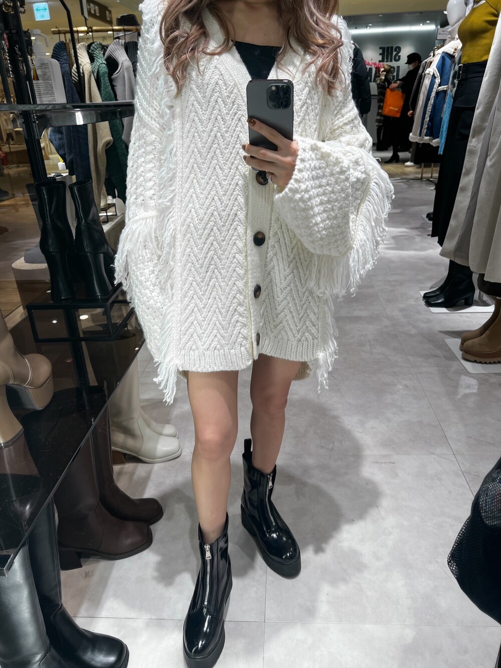 ホワイト系のカーディガン/ボレロ、ブラック系のスウェットパンツ、ブラック系のブーツを着用したレディースの冬コーディネートの6枚目の写真