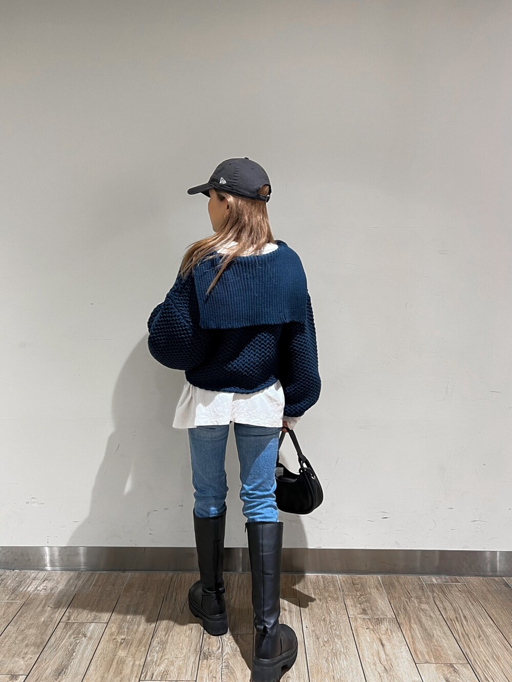 ブラック系のブーツ、ブルー系のニット/セーター、ブラック系のハンドバッグを着用したレディースの冬コーディネートの3枚目の写真