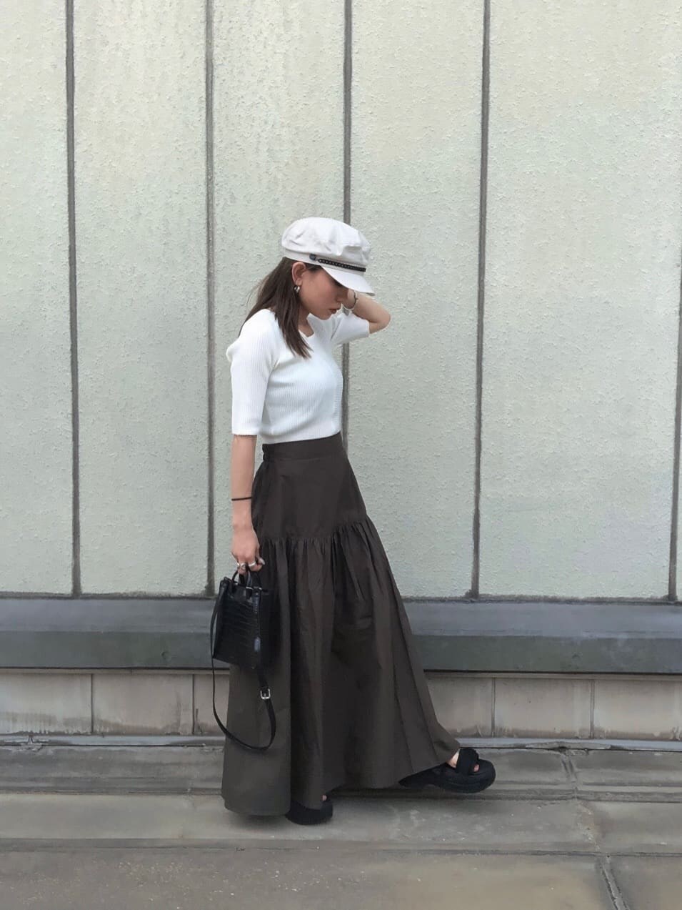 ブラック系のサンダル、ブラック系のショルダーバッグ、ホワイト系のニット/セーターを着用したレディースの夏コーディネートの2枚目の写真
