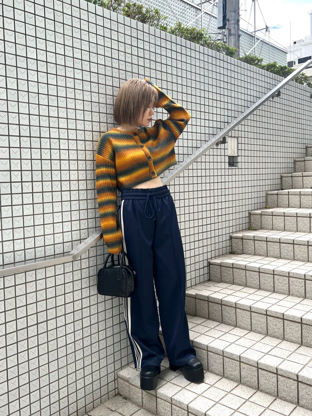 パープル系のカーディガン/ボレロ、ブラック系のブーツ、ブルー系のその他パンツを着用したレディースの秋コーディネートの5枚目の写真