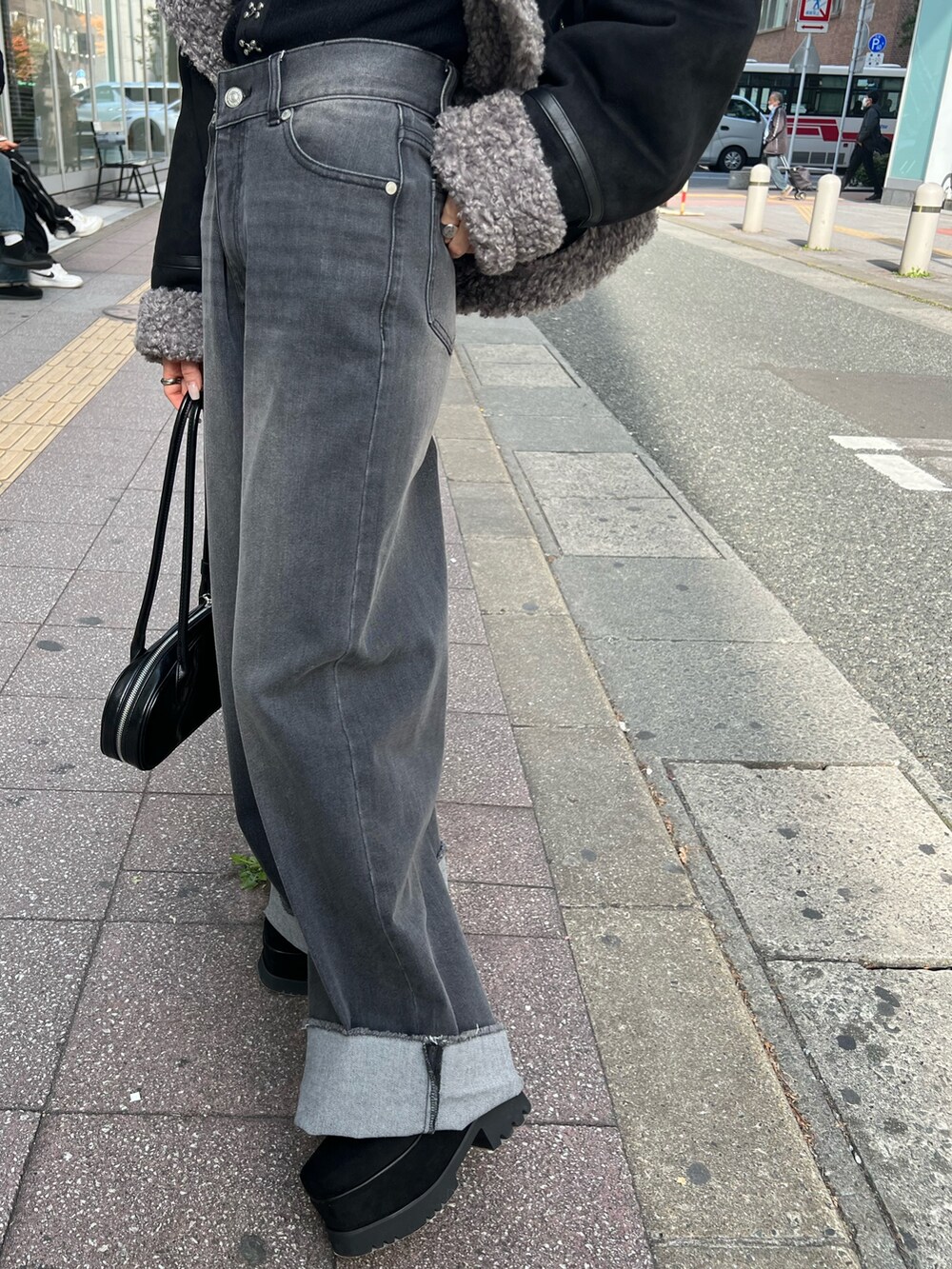 グレー系のデニムパンツ、ブラック系のニット/セーター、ブラック系のブーツを着用したレディースの冬コーディネートの8枚目の写真