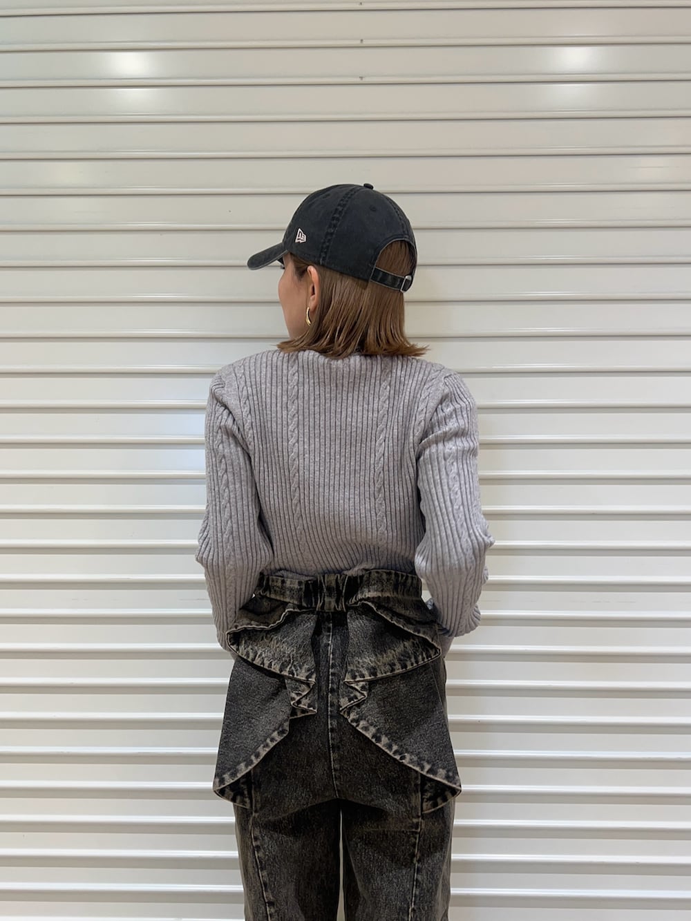 グレー系のニット/セーター、ブラック系のデニムパンツ、ブラック系のキャップを着用したレディースの冬コーディネートの5枚目の写真