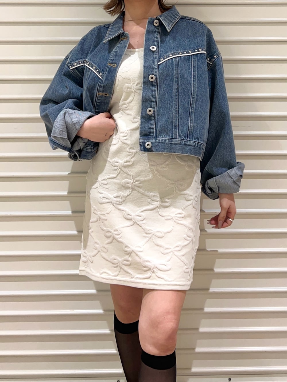 ブルー系のデニムジャケット、ホワイト系のワンピース、ブラック系のキャップを着用したレディースの春コーディネートの6枚目の写真