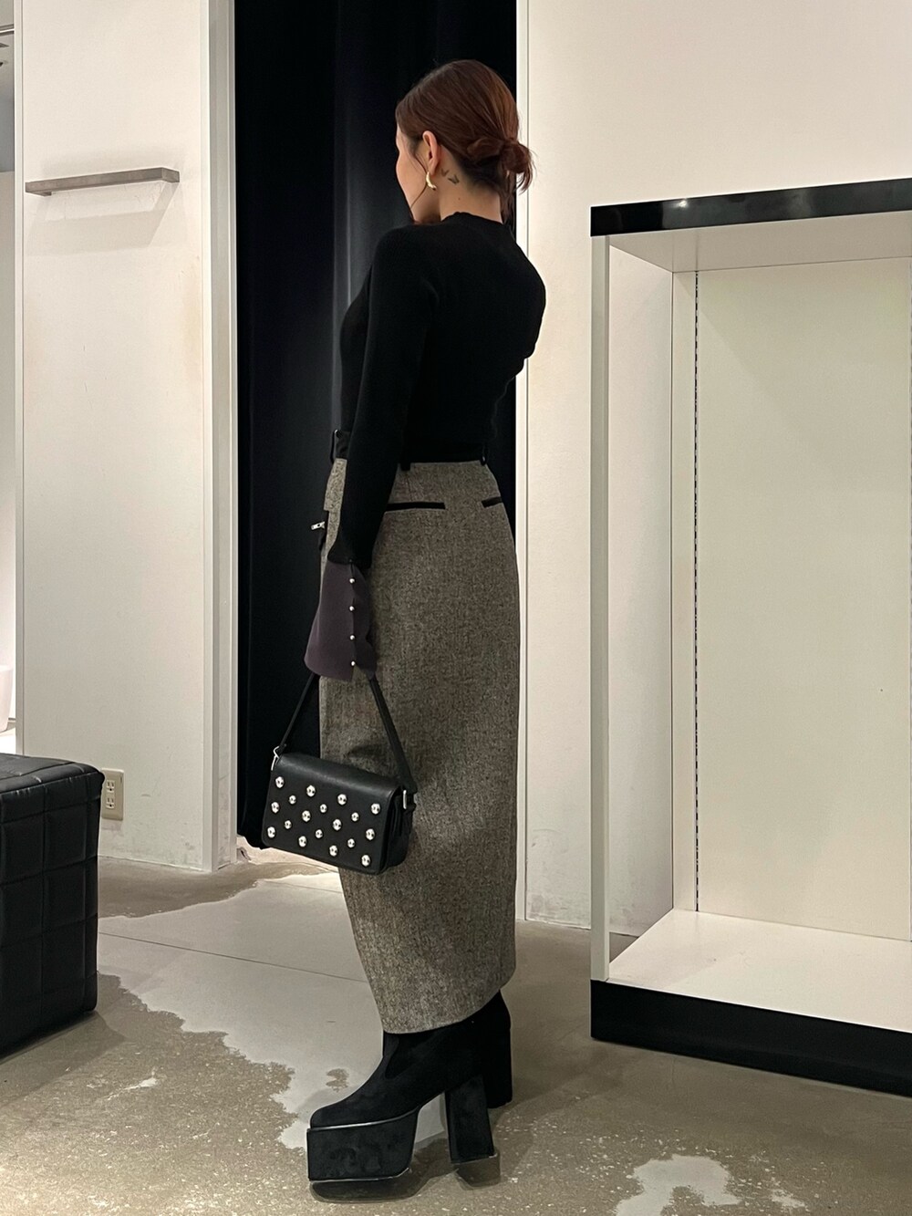 ブラック系のニット/セーター、ブラック系のスカート、ブラック系のブーツを着用したレディースの秋コーディネートの2枚目の写真