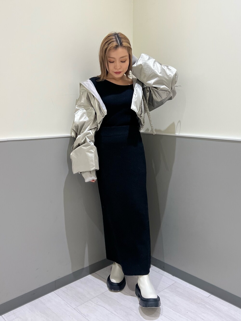 ブラック系のニット/セーター、シルバー系のブルゾン、ブラック系のスカートを着用したレディースの冬コーディネートの2枚目の写真