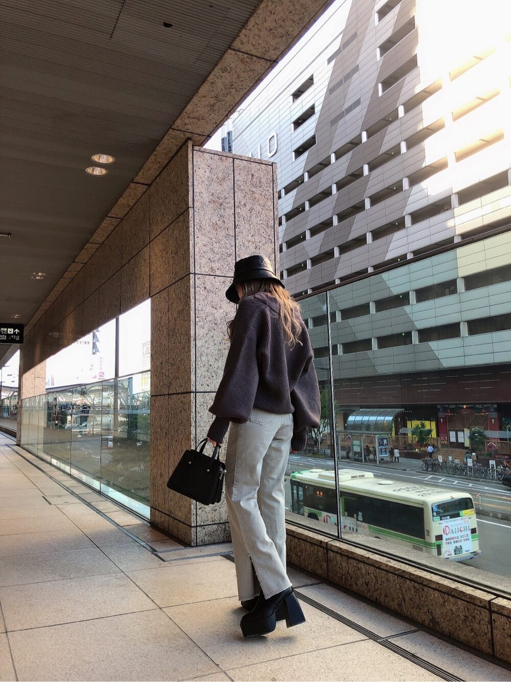 グレー系のデニムパンツ、グレー系のニット/セーター、ブラック系のハンドバッグを着用したレディースの秋コーディネートの3枚目の写真