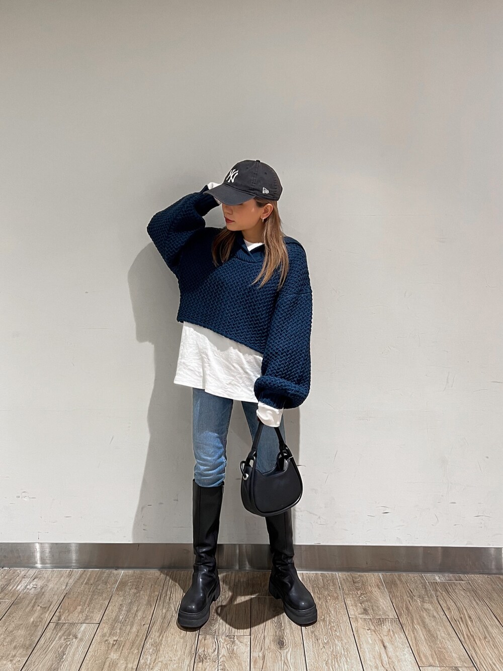 ブラック系のブーツ、ブルー系のニット/セーター、ブラック系のハンドバッグを着用したレディースの冬コーディネートの2枚目の写真