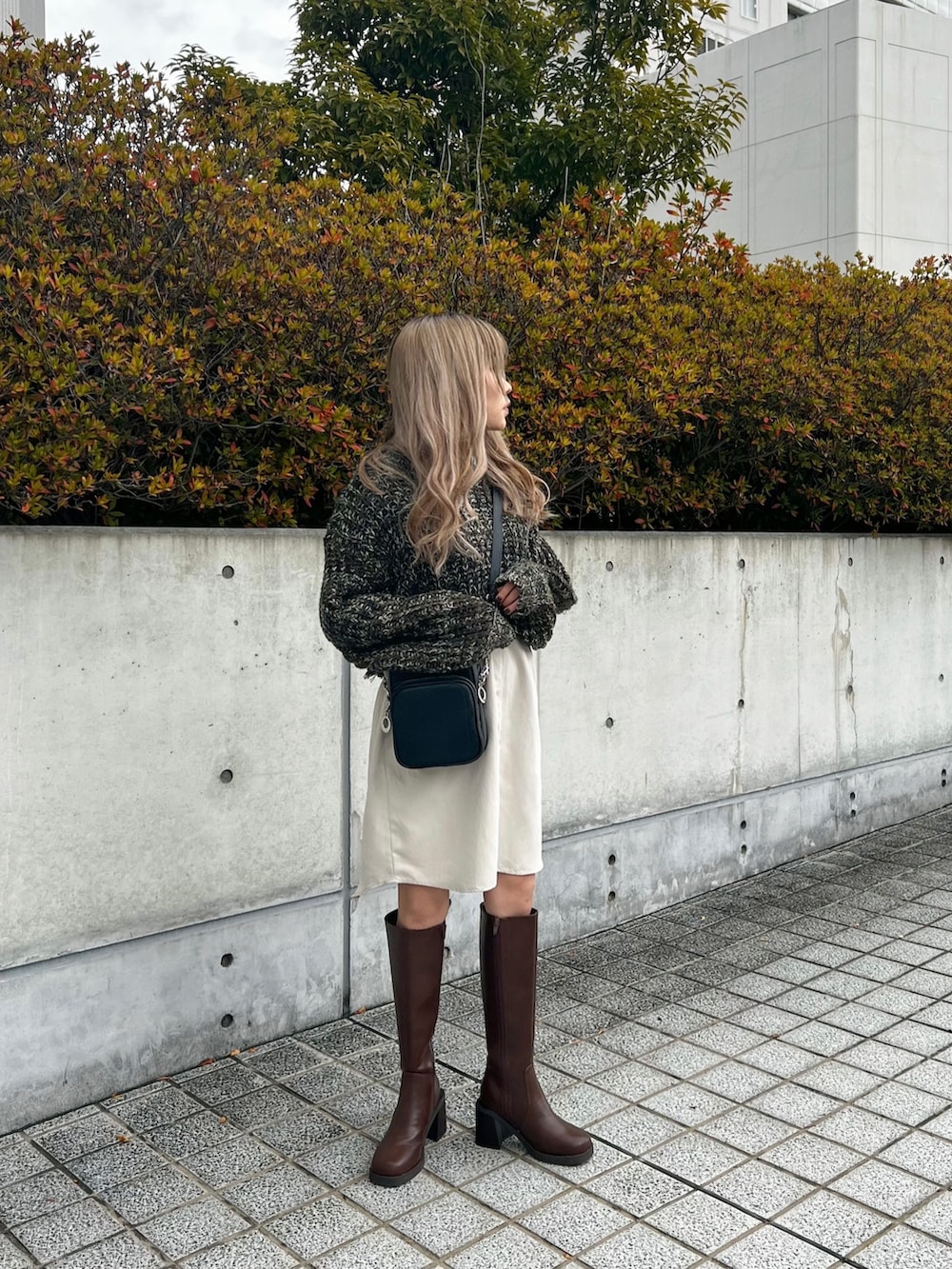 グリーン系のワンピース、ブラック系のショルダーバッグ、ブラウン系のブーツを着用したレディースの冬コーディネートの4枚目の写真