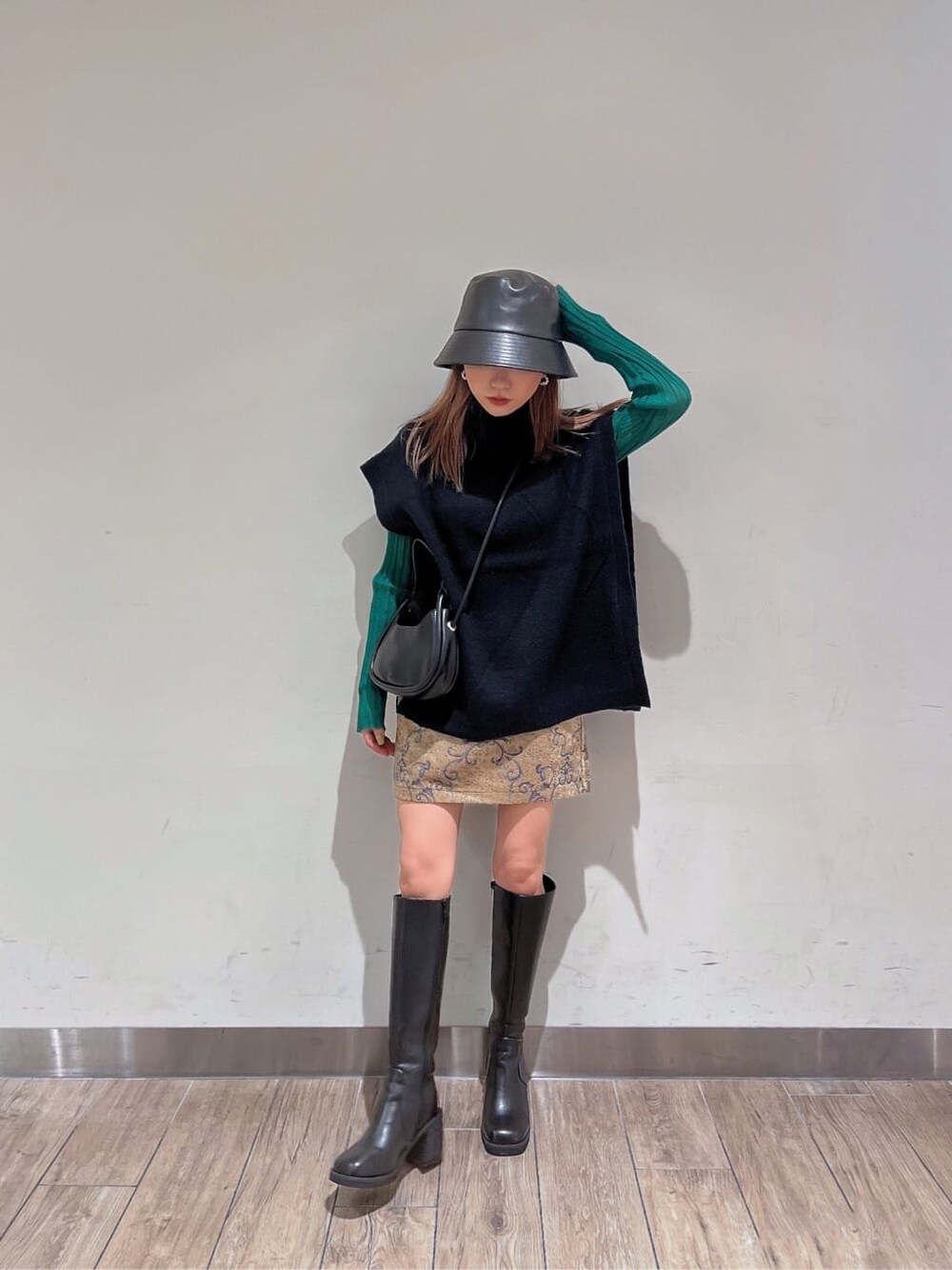 ブラック系のブーツ、グリーン系のニット/セーター、ブラウン系のスカートを着用したレディースの秋コーディネートの2枚目の写真