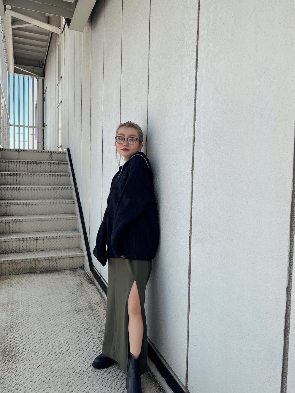 グリーン系のスカート、ブラック系のブーツ、ブラック系のニット/セーターを着用したレディースの秋コーディネートの3枚目の写真