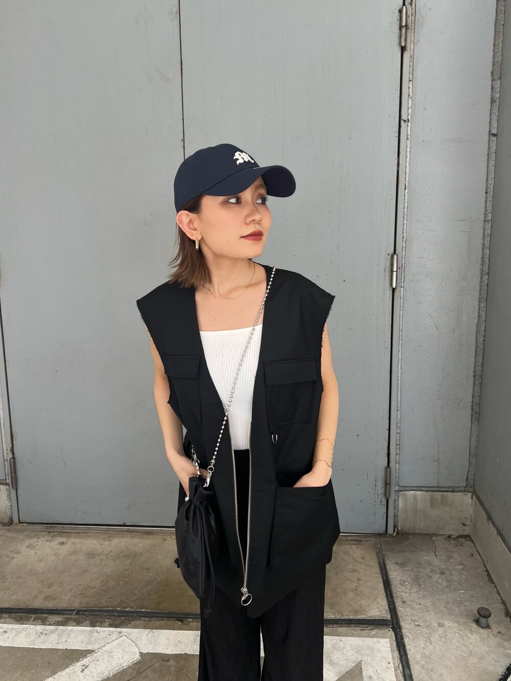 ブラック系のベスト、ホワイト系のニット/セーター、ブルー系のキャップを着用したレディースの夏コーディネートの5枚目の写真